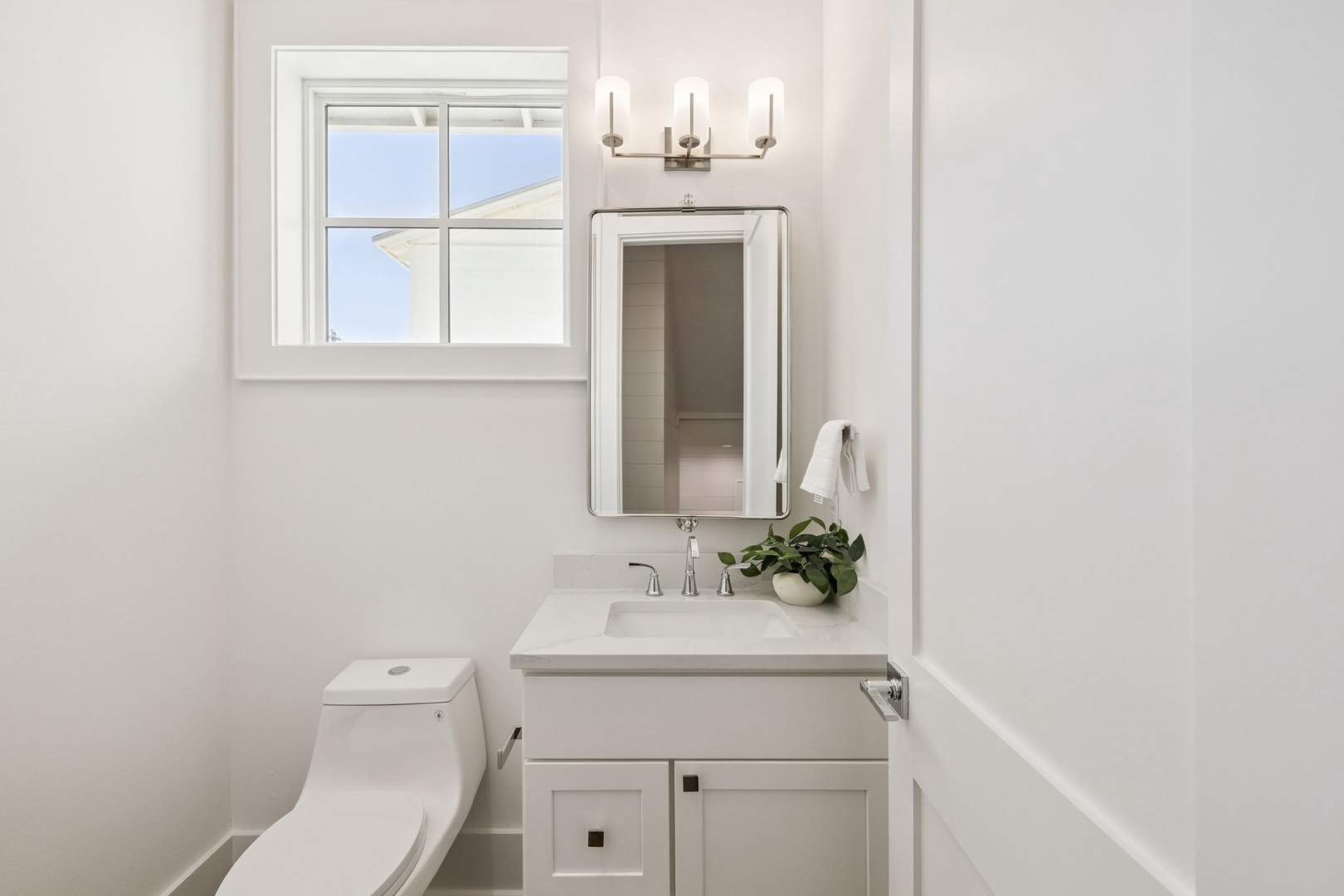 Step into this pristine powder room where natural light streams through the window, illuminating clean lines and modern fixtures for your comfort.