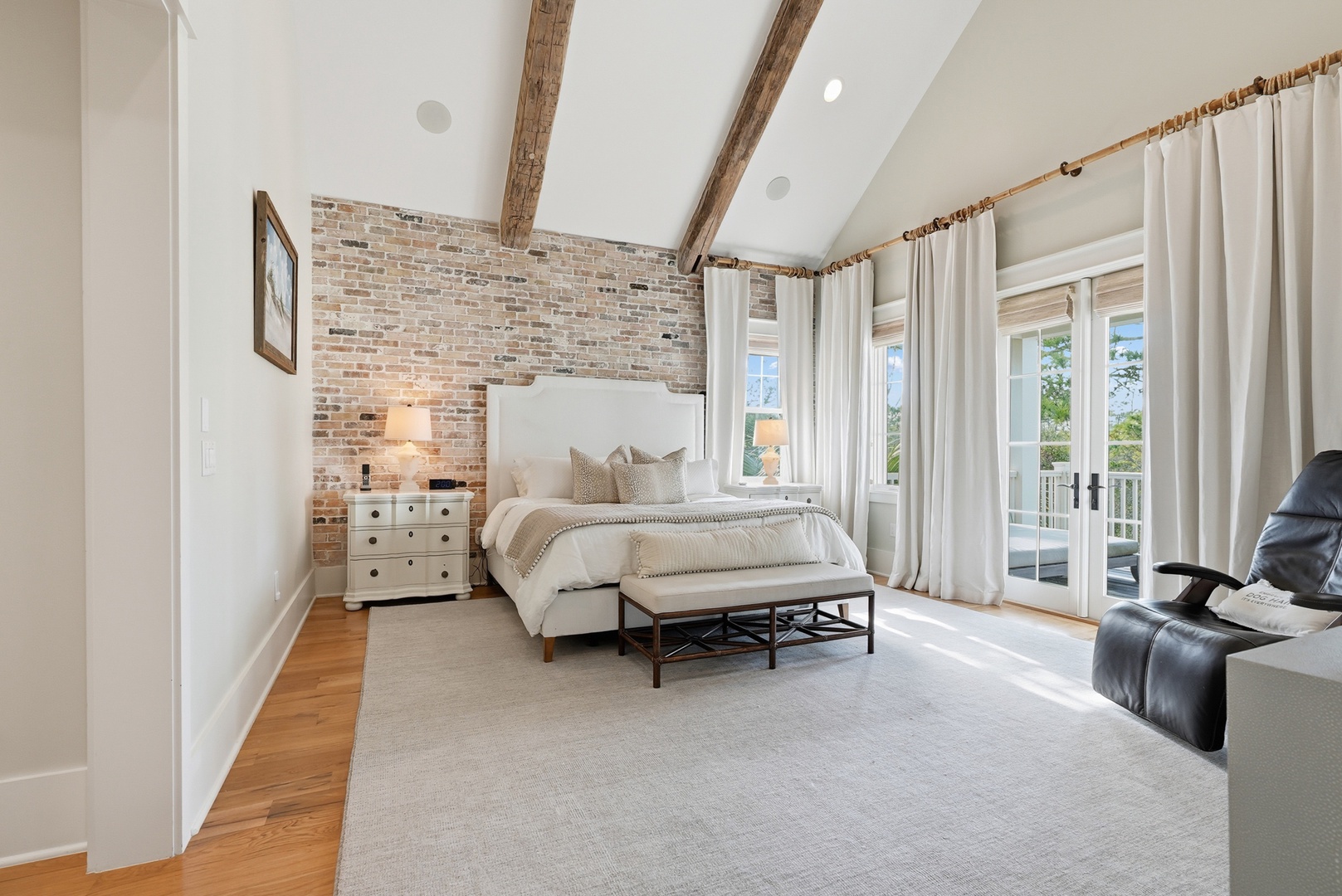 Step into your serene retreat with vaulted ceilings, rustic exposed beams, and a calming brick accent wall. French doors flood your space with natural light and open to your private balcony, perfect for relaxing.