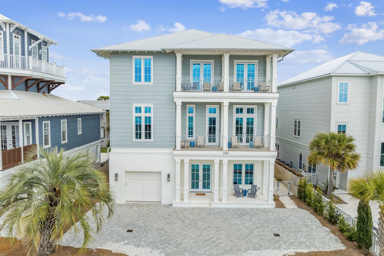 Beautiful three-story coastal home with multiple balconies and tropical landscaping in a charming beachside neighborhood.