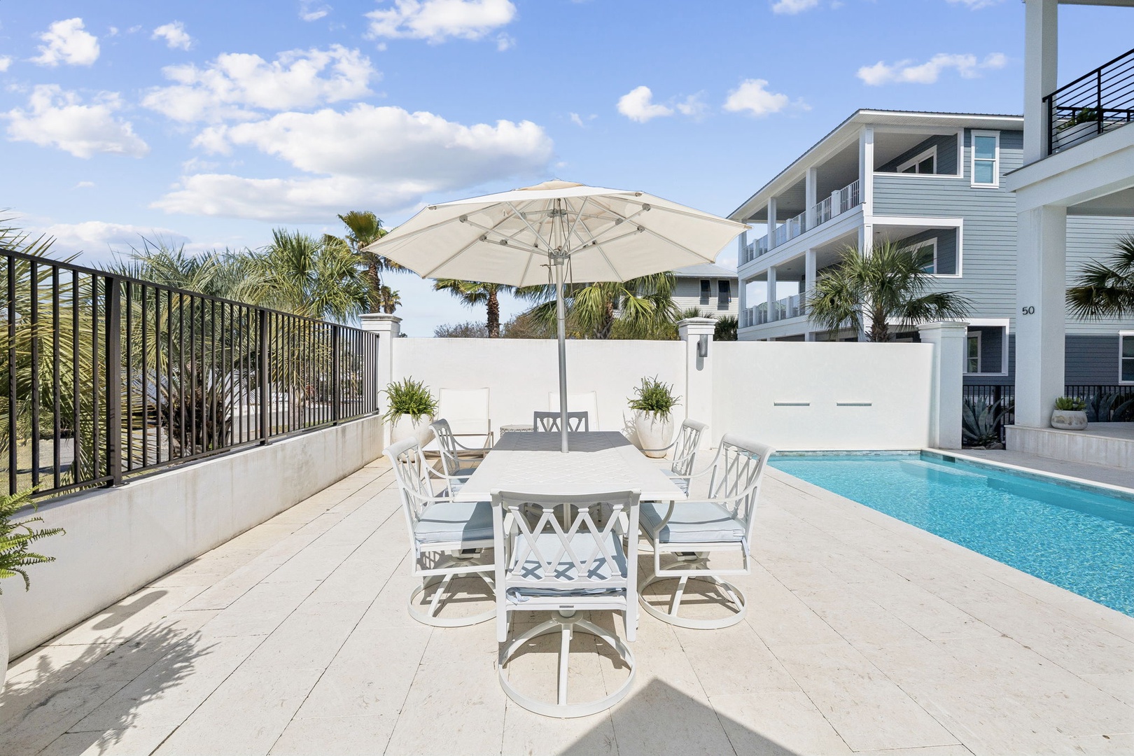 Your private poolside dining awaits - gather around this elegant table under tropical skies for memorable meals by the sparkling water.