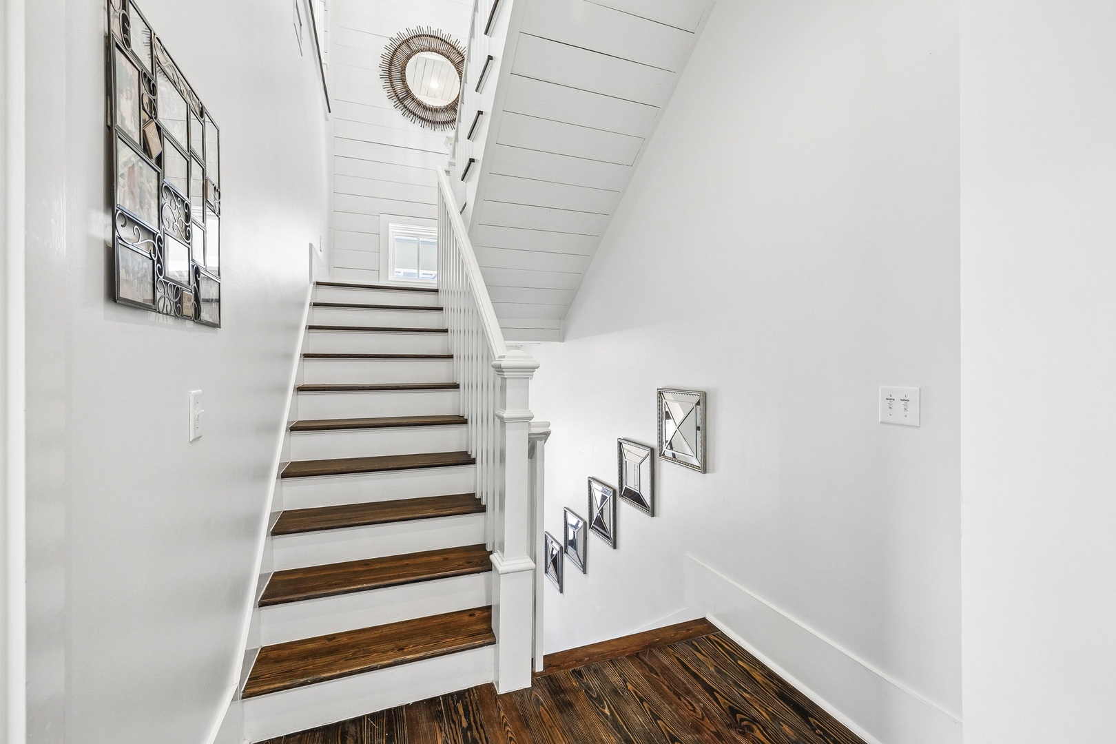 Charming staircase with warm wood tones and coastal touches invites you to explore the upper level of your retreat.