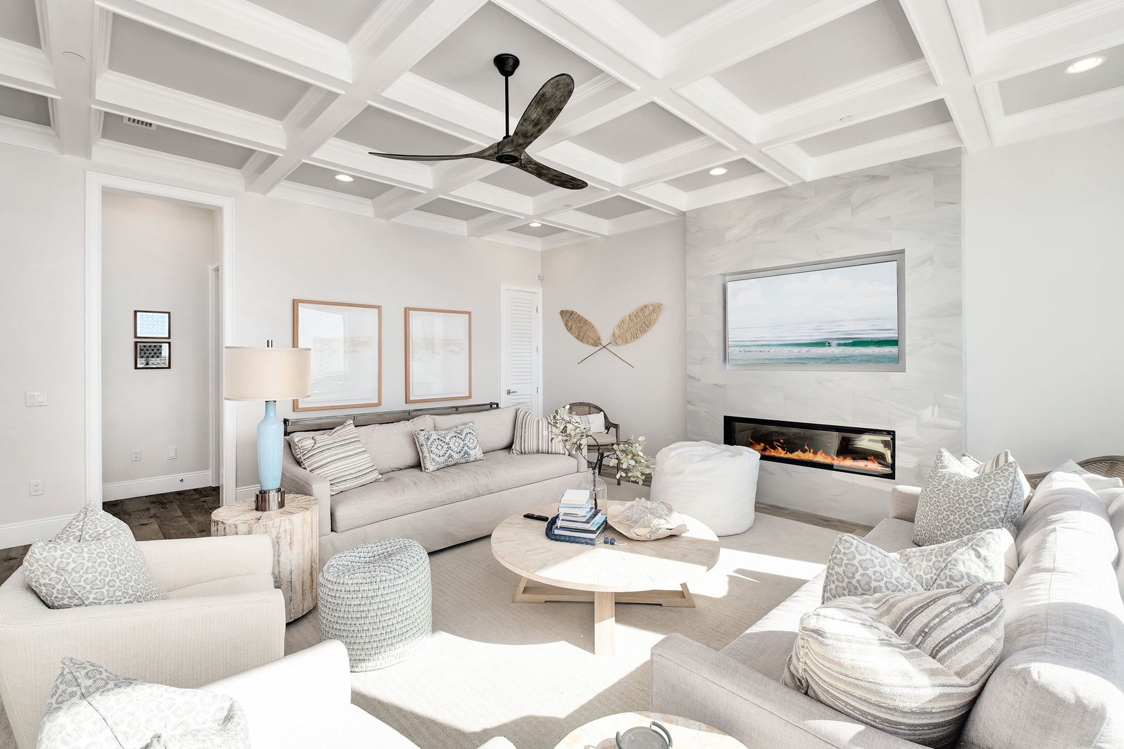 Unwind in your elegant living space with a cozy fireplace, stylish coastal decor, and sophisticated coffered ceiling that creates perfect ambiance.