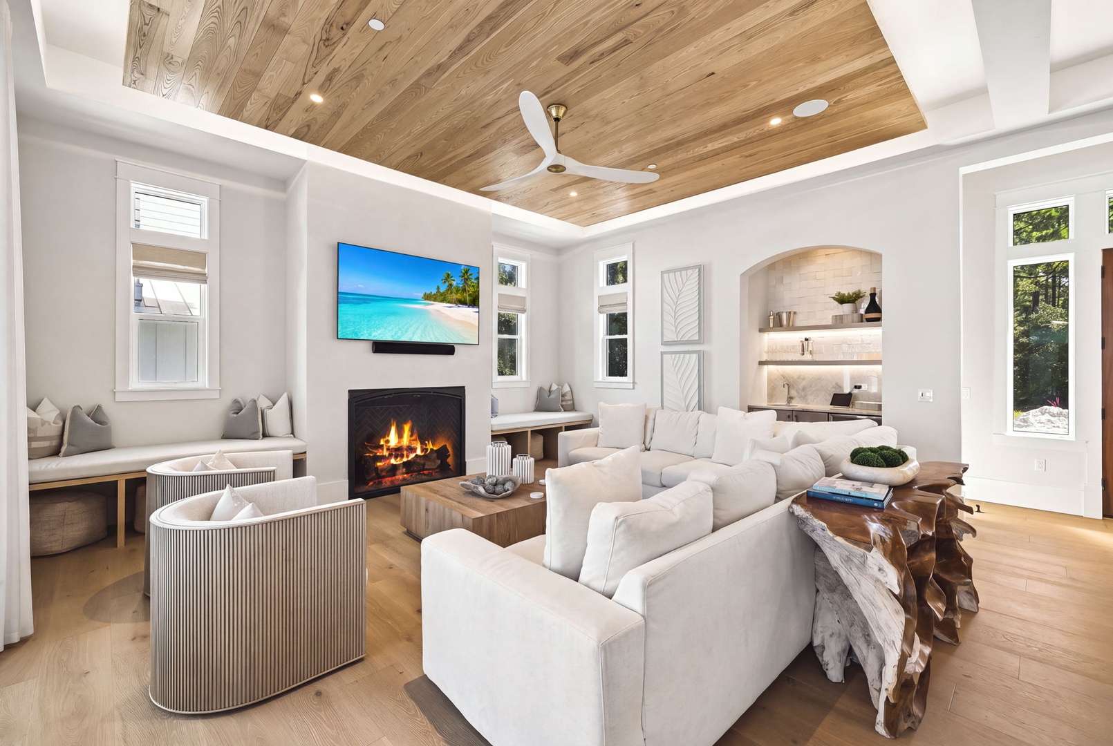 Sink into plush seating beneath a stunning wood-beam ceiling, where natural light fills this elegant living space. Warm up by the fireplace or step out to explore the lush surroundings visible through your windows.