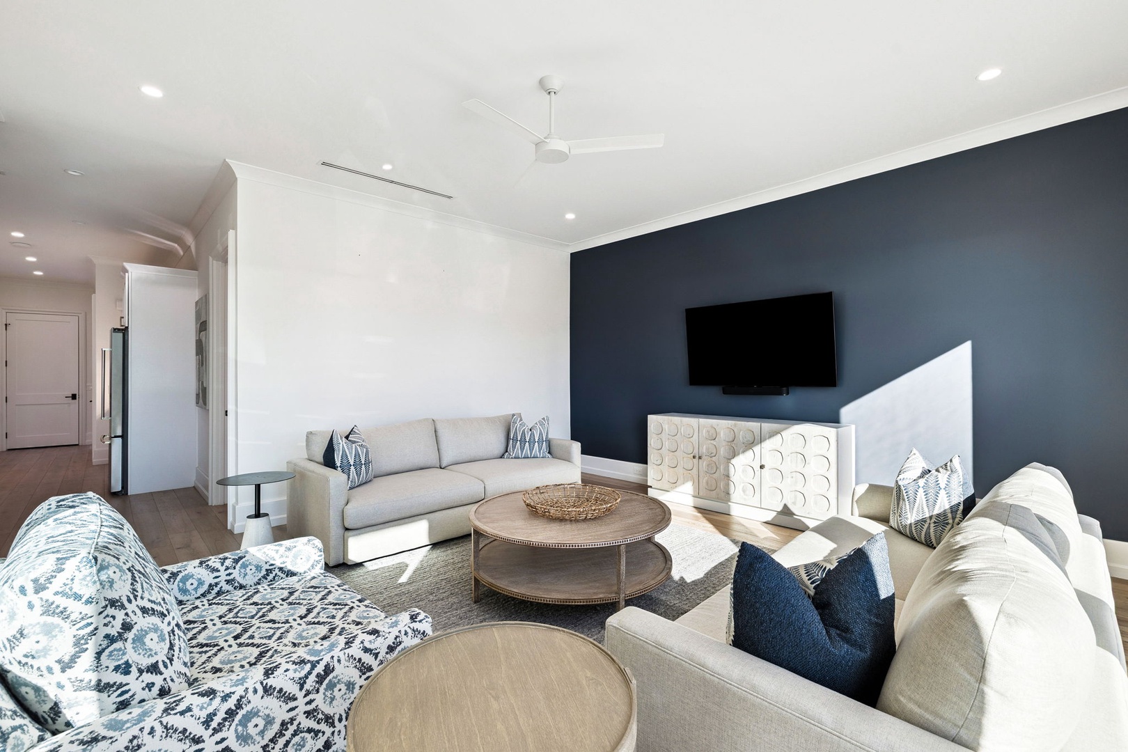 Your spacious living room welcomes you with plush seating, modern coastal décor, and a large TV for relaxing evenings.