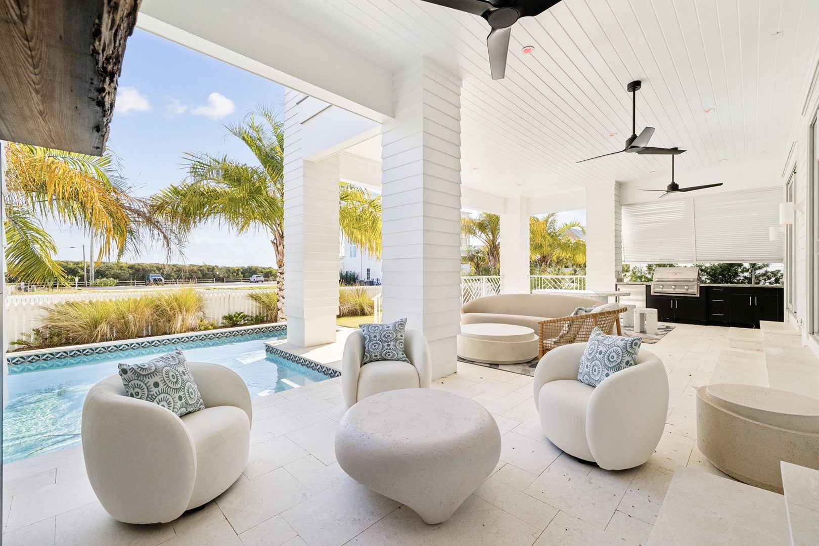 Relax in luxurious poolside comfort with plush seating, ceiling fans, and tropical views creating your perfect outdoor retreat.