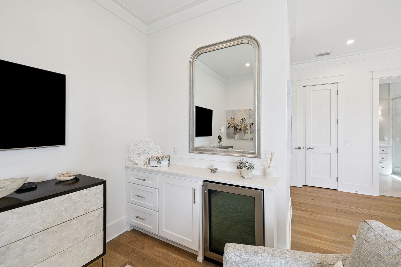 Your elegant bedroom features a stylish built-in dresser, wall-mounted TV, and tasteful decor creating a serene retreat.