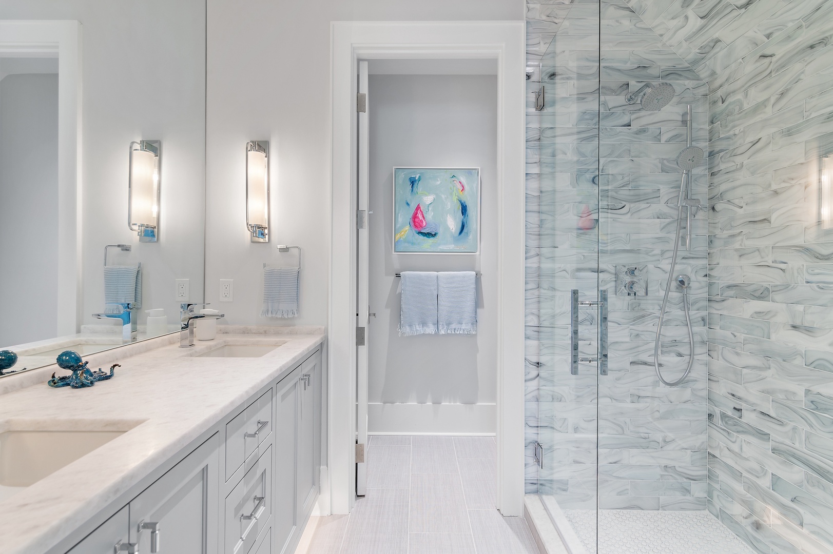 Unwind in your elegantly designed bathroom, where cool blue tones and stunning marble-style tile create a spa-like sanctuary for your morning routine.