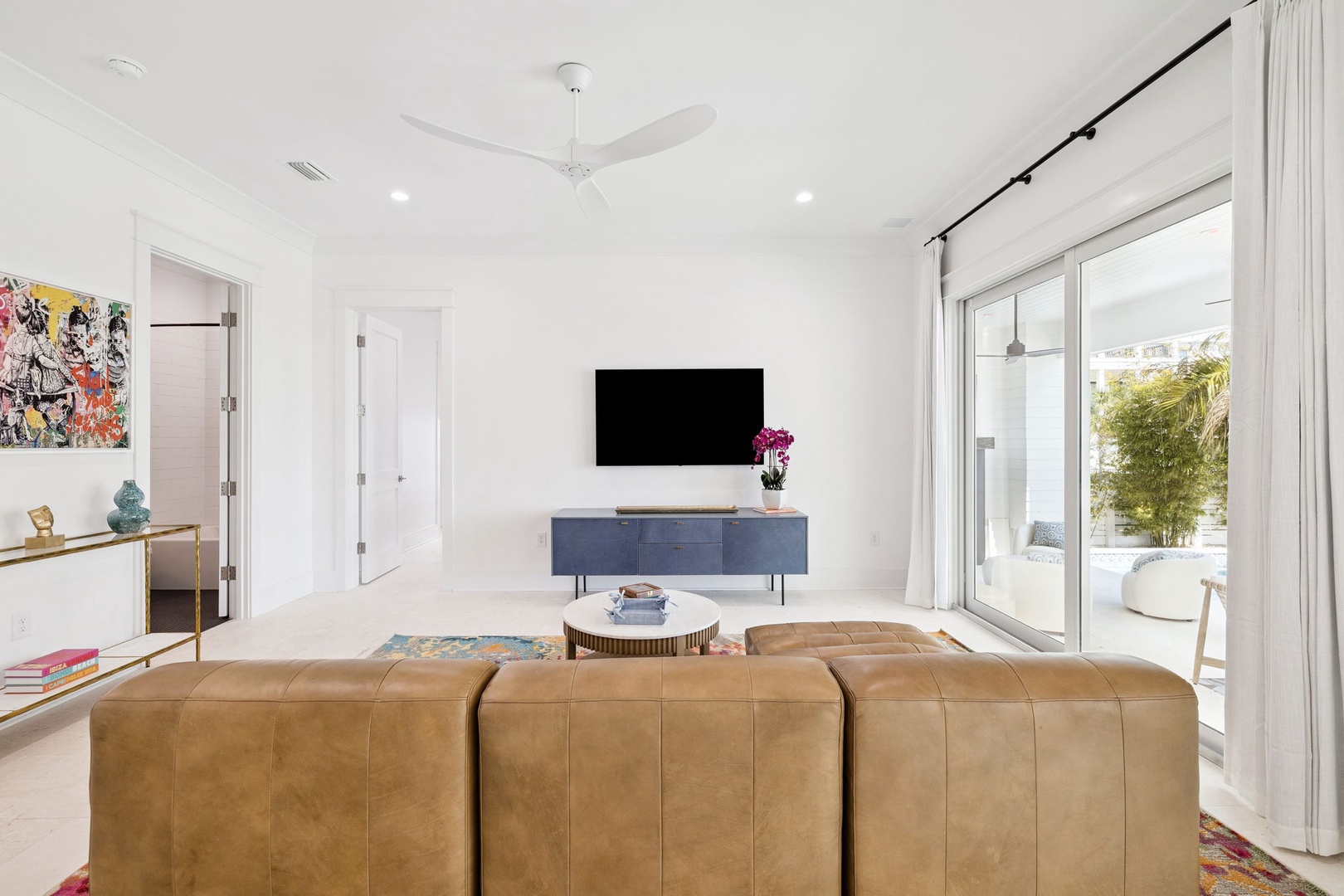 Relax in this bright, modern living room with sleek leather seating and entertainment center, perfectly positioned near your private outdoor terrace.