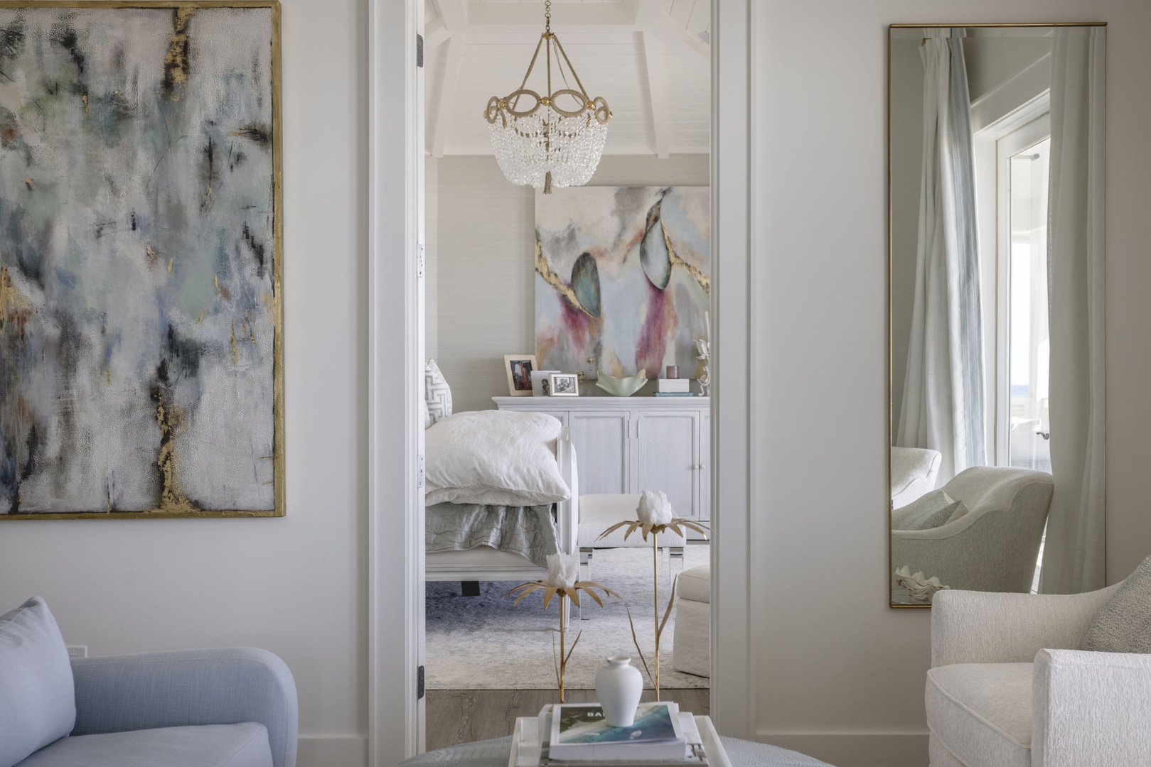 Sunlight spills through the doorway, inviting you to explore the elegant bedroom beyond, where soft linens and thoughtful art create a serene, restful retreat.