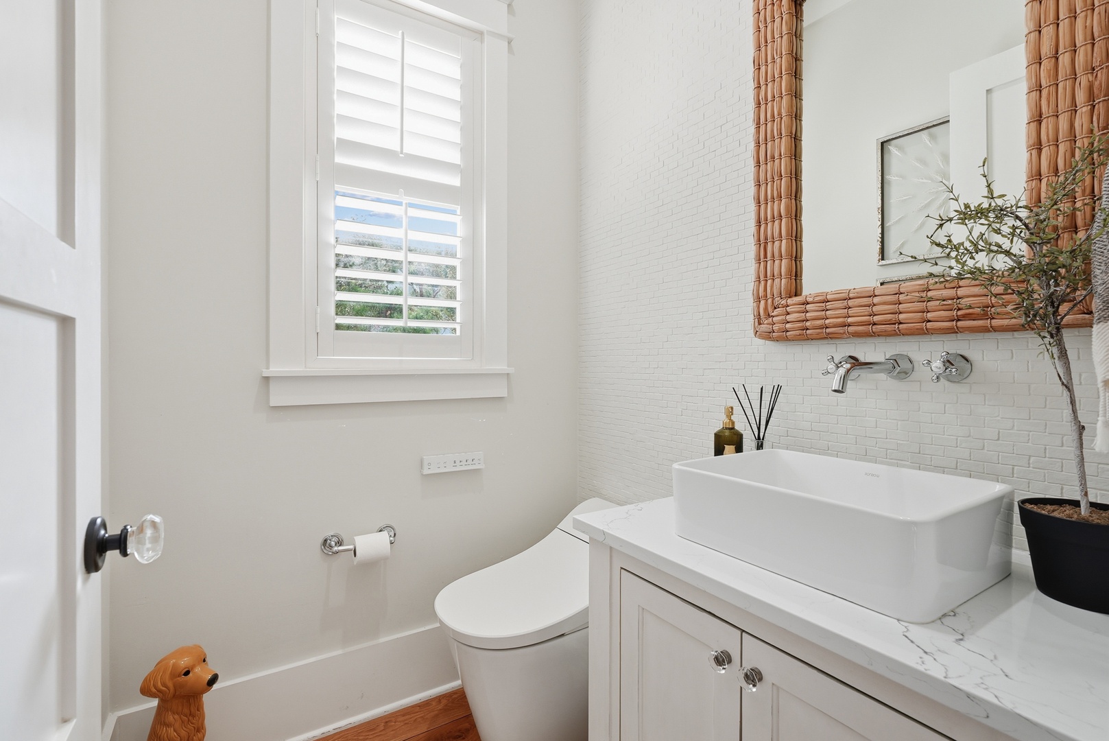 Freshen up in this bright, beautifully tiled bathroom featuring modern fixtures, a vessel sink, and thoughtful coastal touches like the woven mirror—your serene morning retreat.