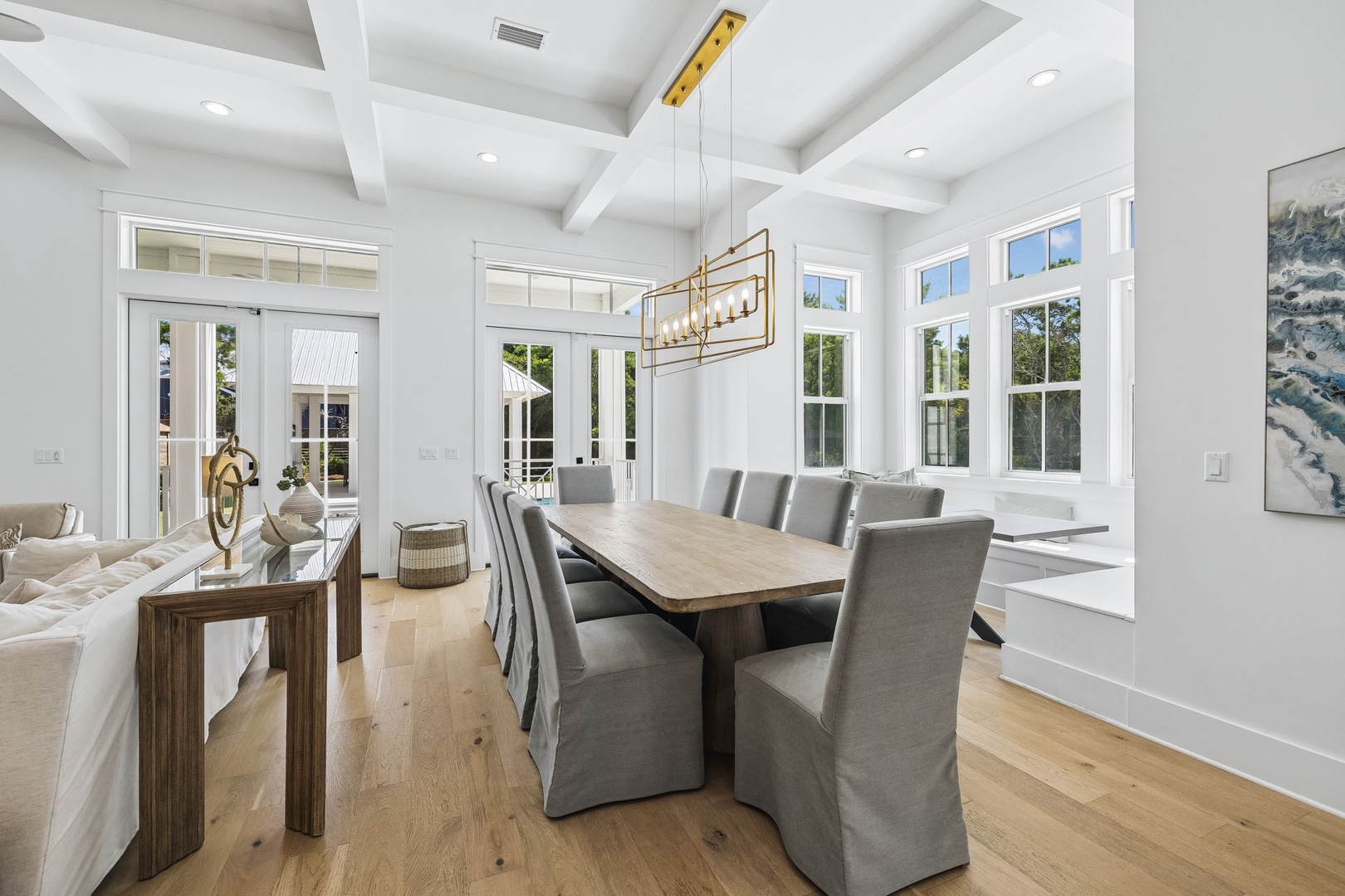 You'll love gathering around this elegant dining table beneath a modern chandelier, with natural light pouring through expansive windows and views of the surrounding greenery.