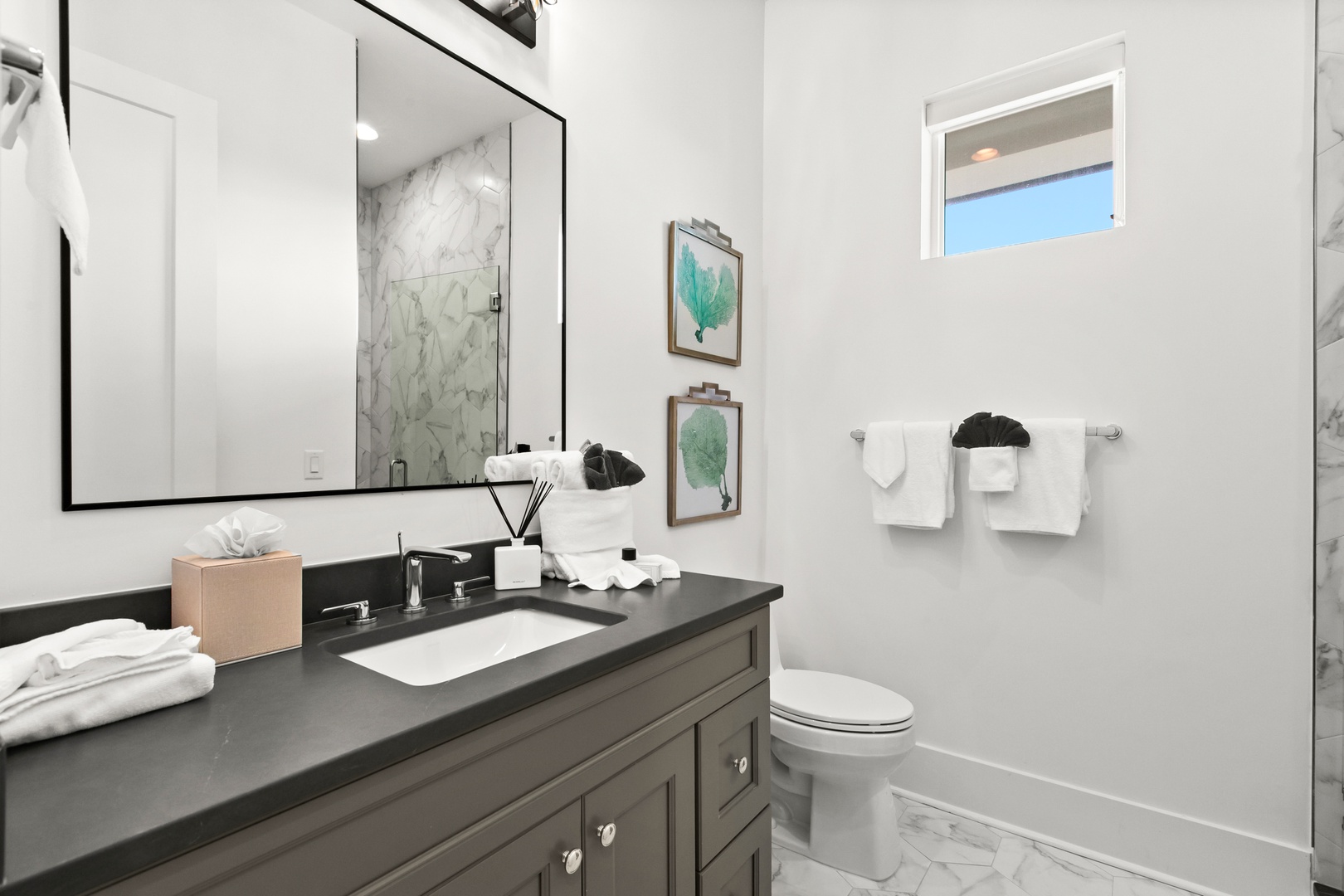 Step into your private retreat where bright marble meets sleek modern fixtures. Crisp white towels and thoughtful touches welcome you to unwind after a day exploring the coast.