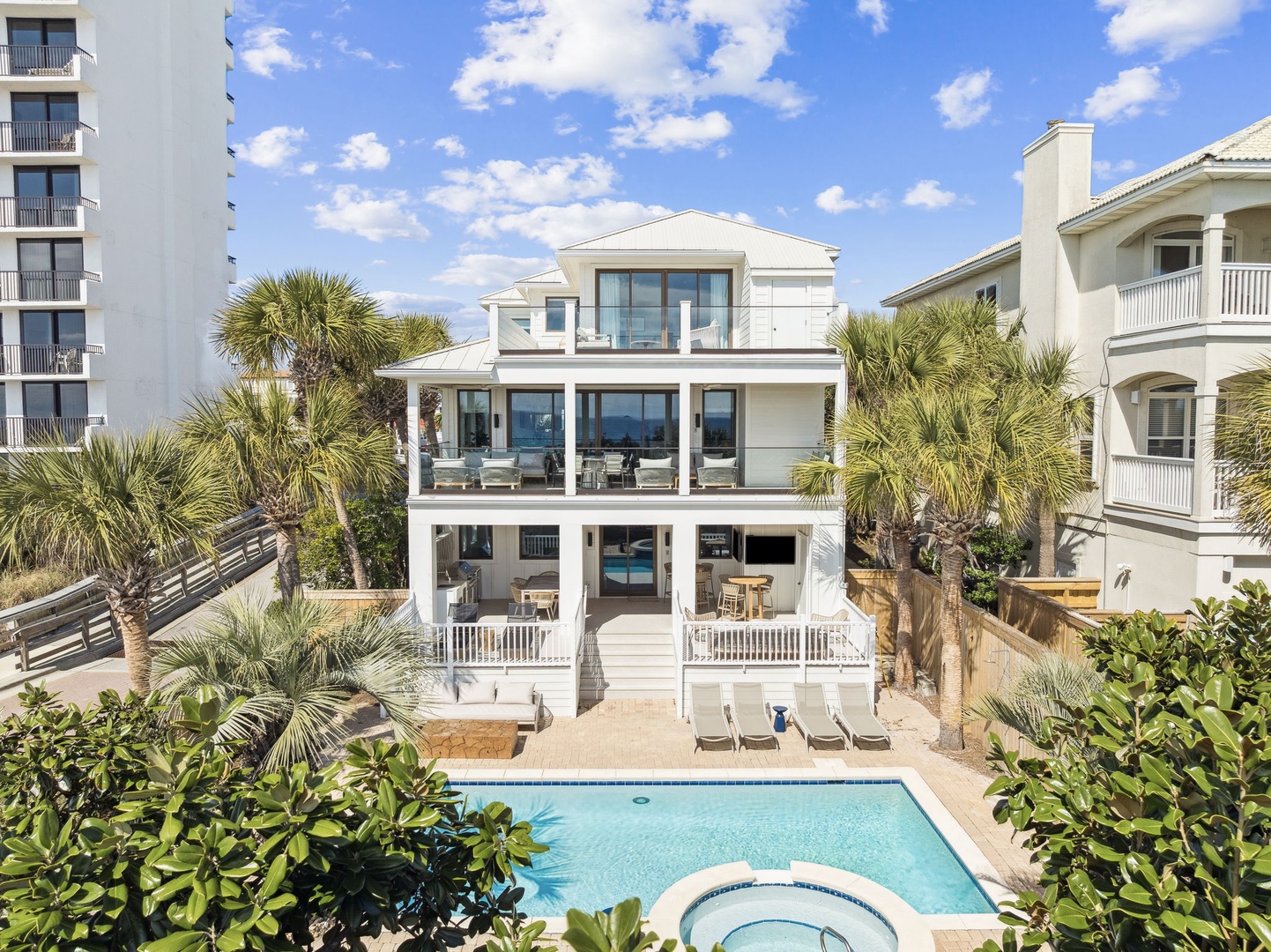 Stunning three-story beachfront home with private pool and hot tub, surrounded by tropical palms in a prime coastal location.