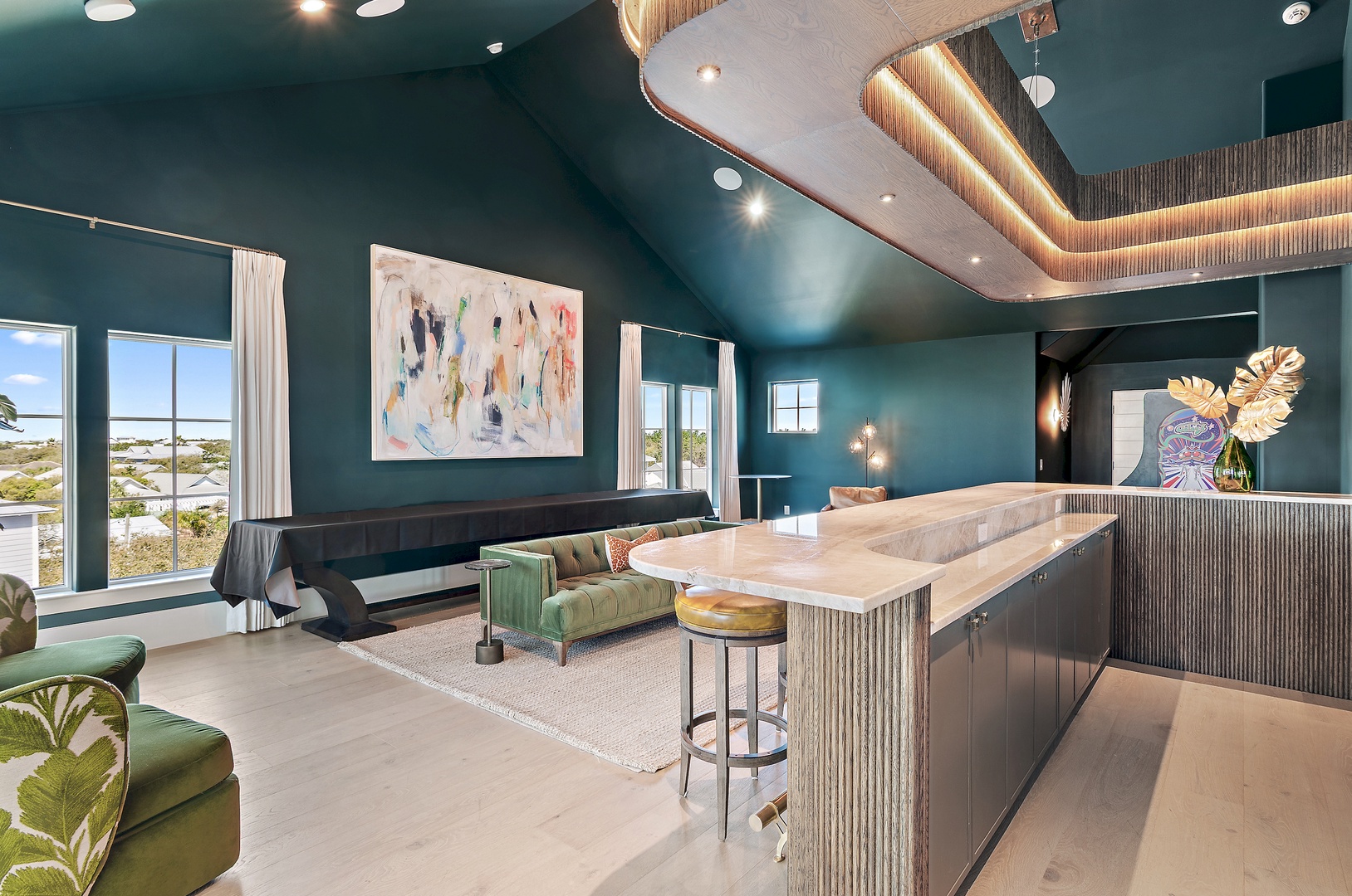 Unwind in your open-concept living and kitchen area, where rich teal walls and stunning ceiling details create a sophisticated coastal retreat perfect for entertaining or relaxing after exploring nearby beaches.