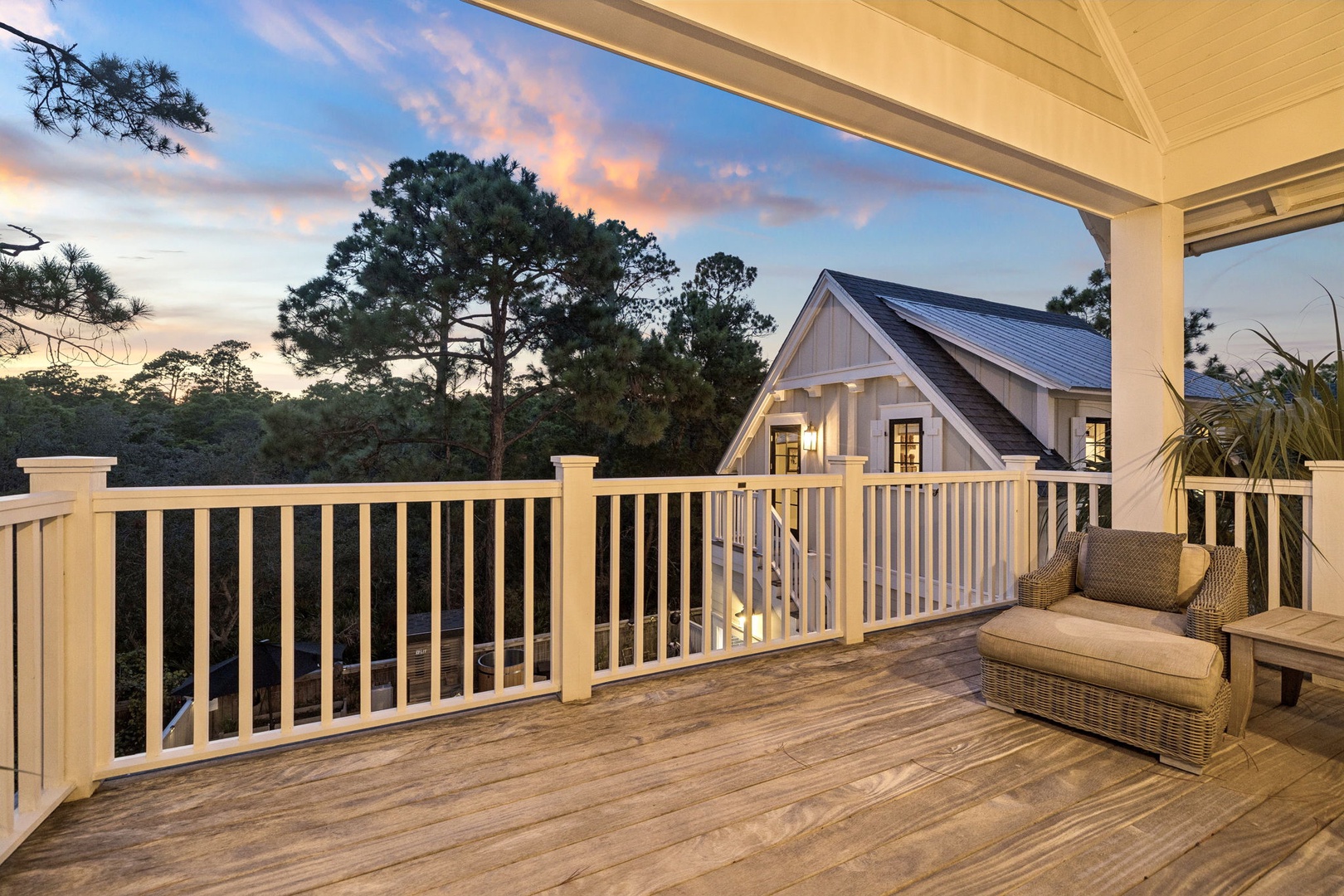 A spacious deck overlooks peaceful woodland, perfect for sunset evenings. The rooftop and natural surroundings create a serene escape framed by towering pines and soft twilight hues.