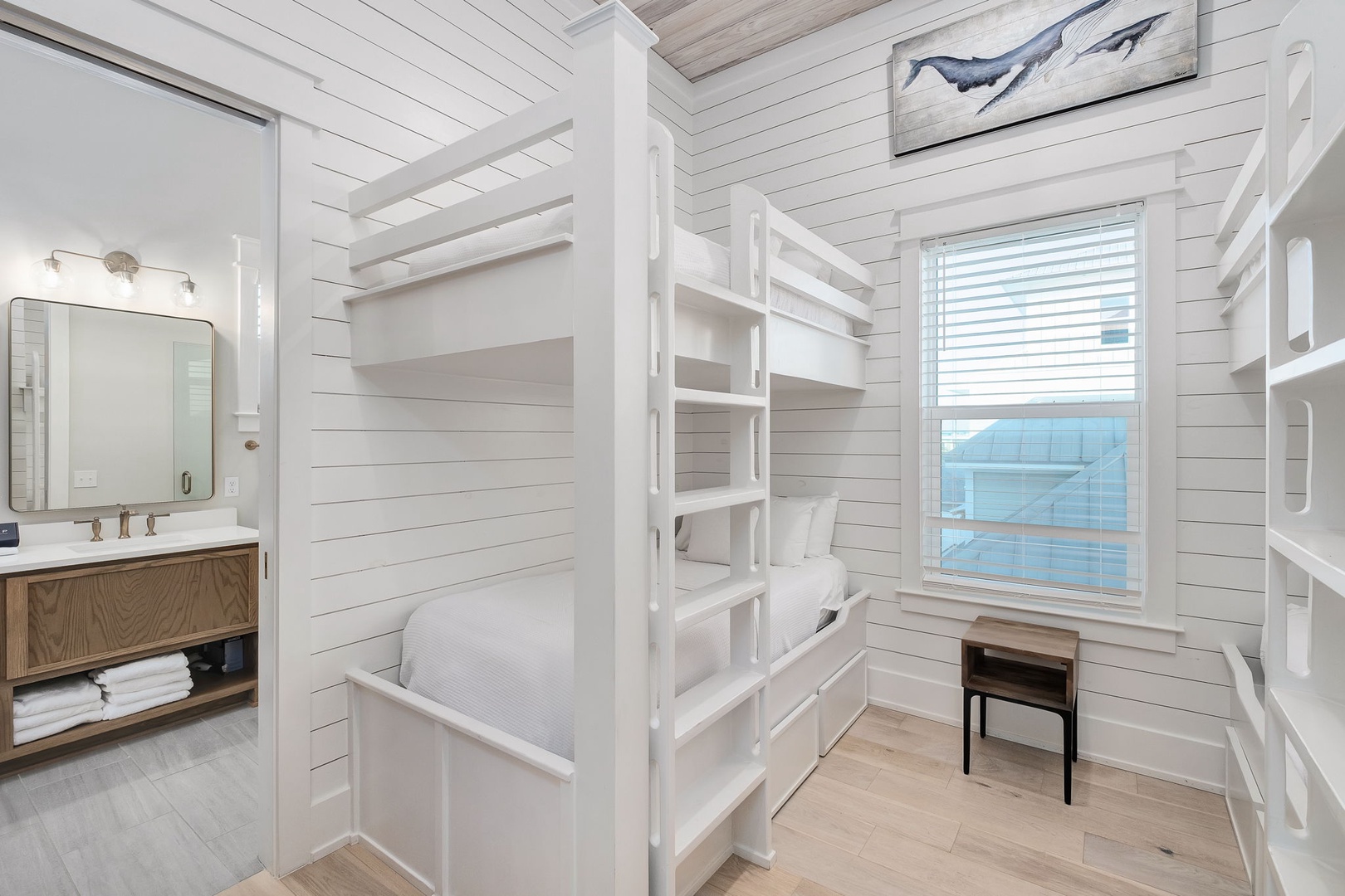 Your coastal bunk room features custom white built-ins and ocean artwork, perfect for kids or groups seeking seaside comfort.