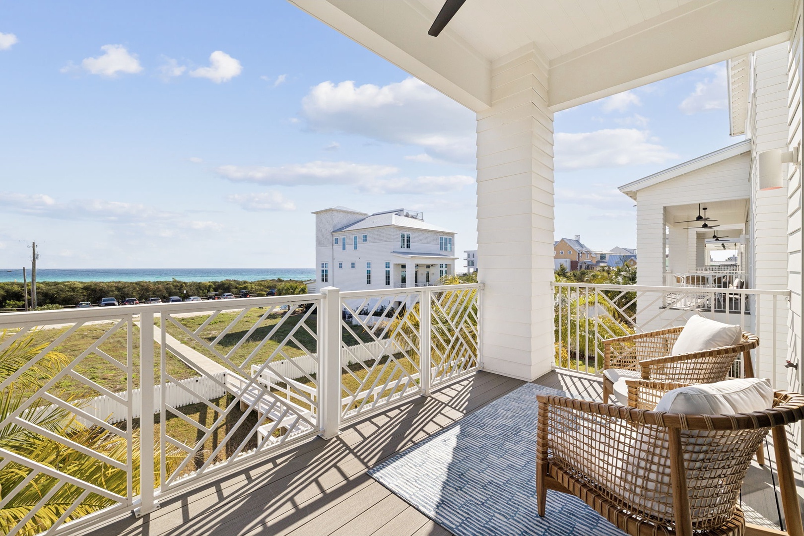 Unwind in your private coastal retreat with wicker seating and ocean glimpses beyond neighboring homes.
