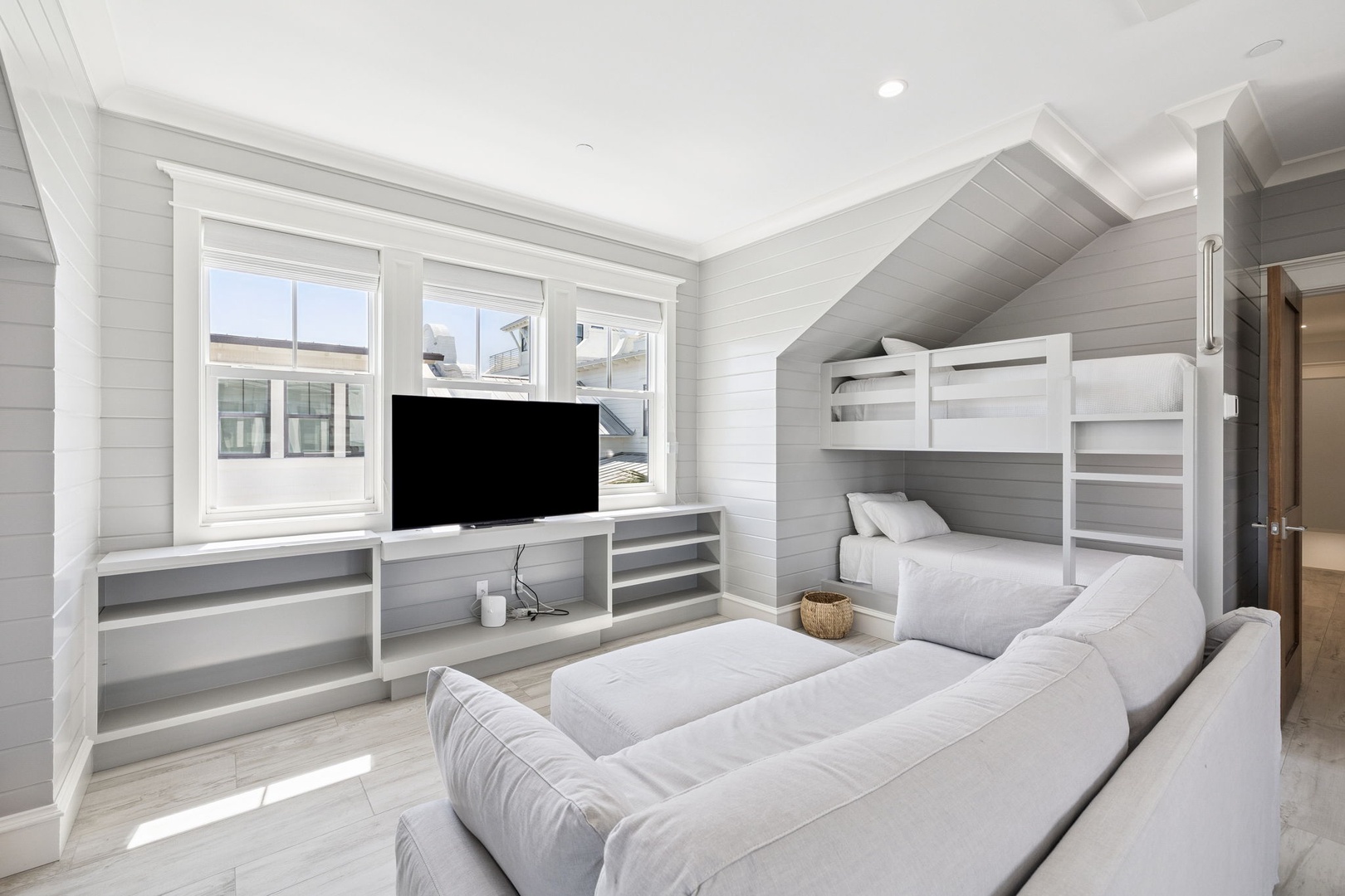 Your coastal retreat features crisp white bunk beds and a plush sofa, perfect for family bonding with built-in entertainment center.