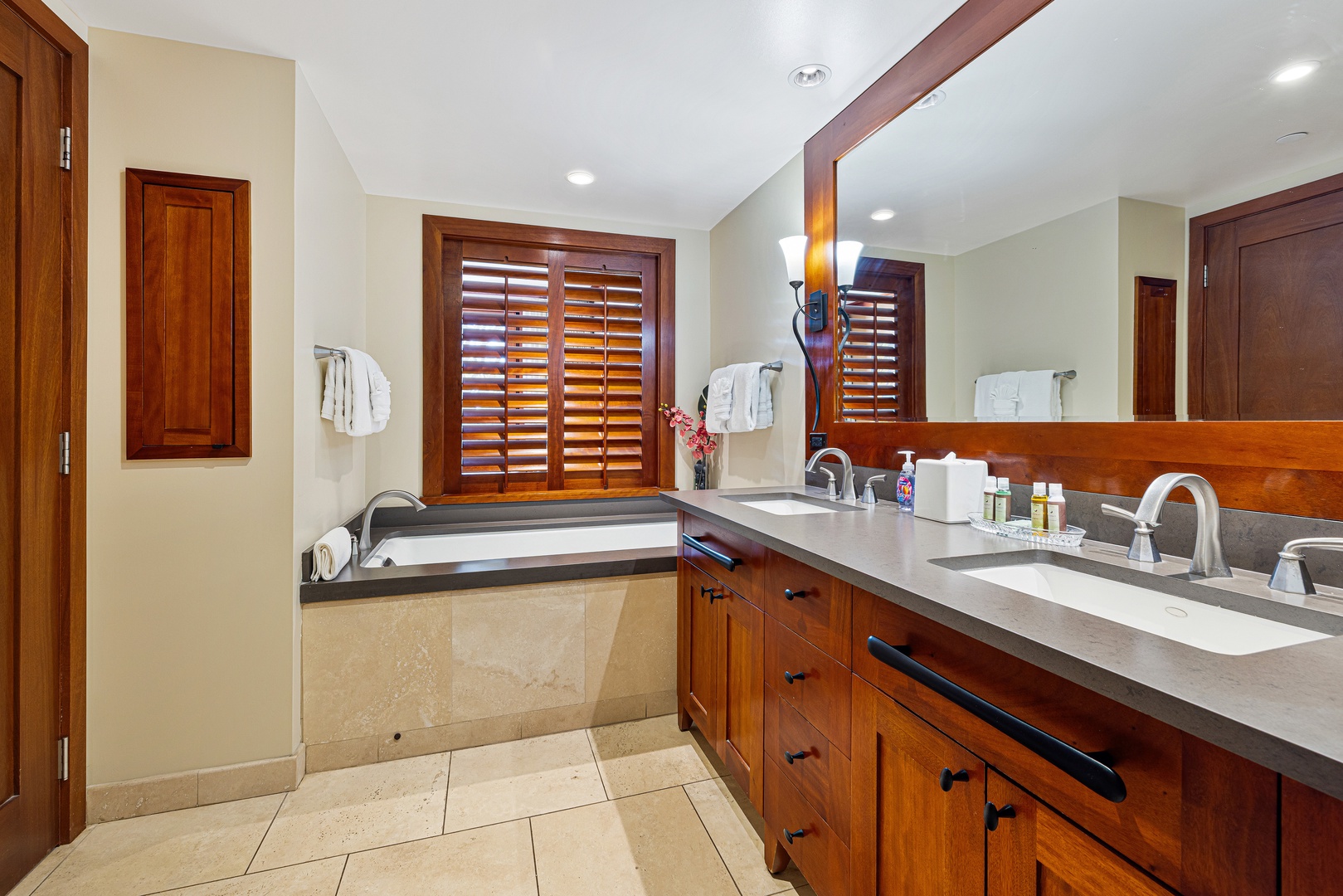 Unwind in your elegant bathroom featuring dual vanities, a soaking tub, and rich wood accents. Plush towels and thoughtful amenities ensure your comfort during your stay.