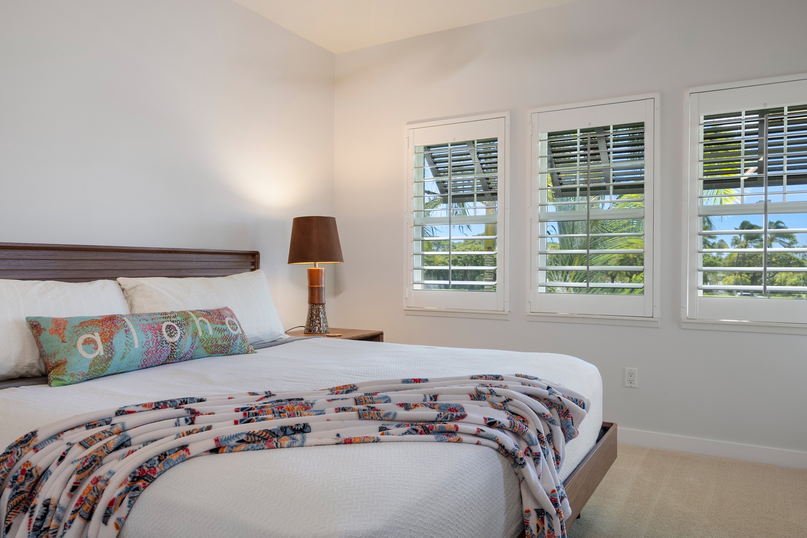 Bright bedroom, where soft linens and tropical views through plantation shutters create the perfect retreat.