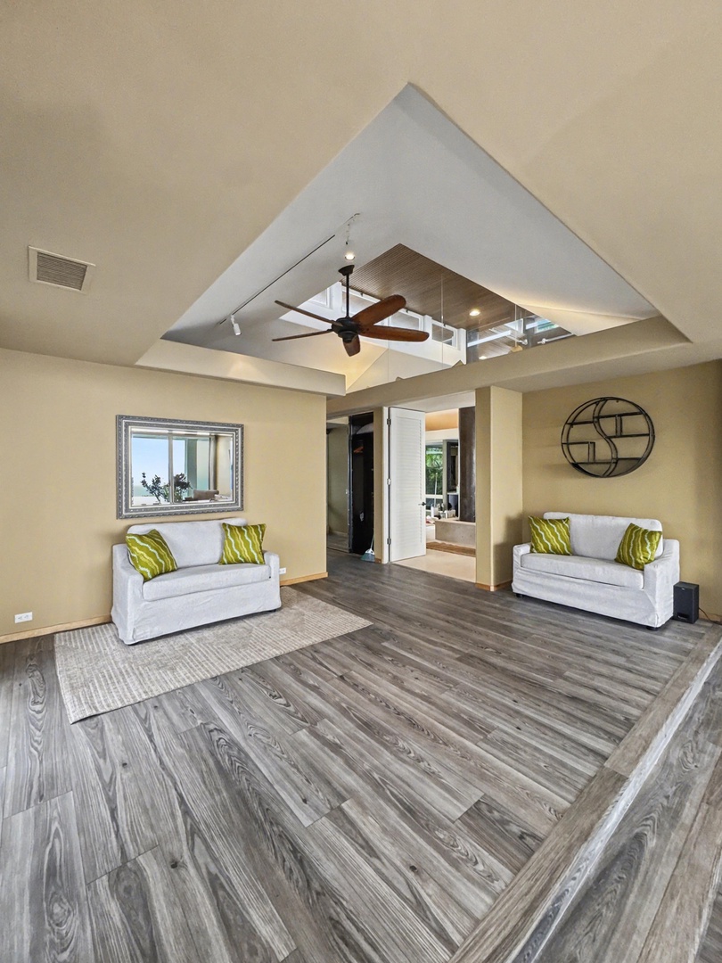 Kailua Kona Vacation Rentals, Hale Nai'a - Your primary bedroom features a striking ceiling design with modern lighting, comfortable seating, and beautiful hardwood floors throughout.
