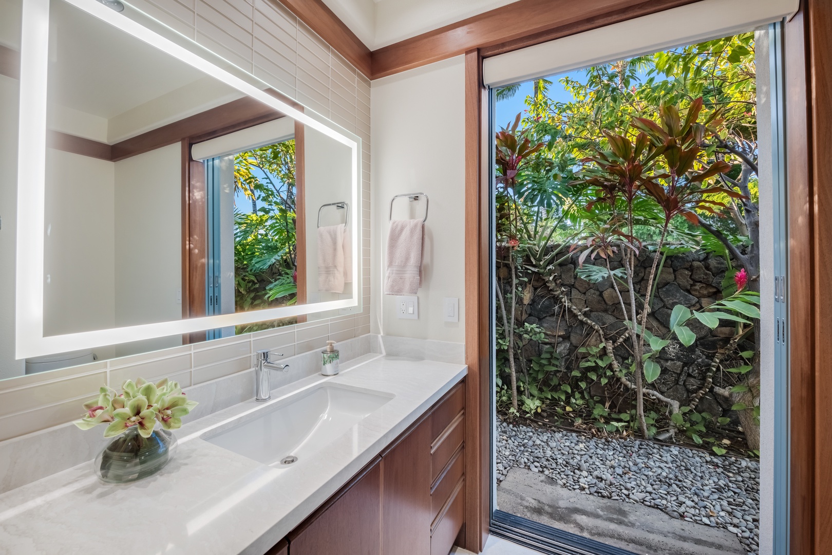Kamuela Vacation Rentals, Champion Ridge Elegance - Guest Suite 3 bright ensuite bathroom with a sleek vanity and access to tropical garden views.
