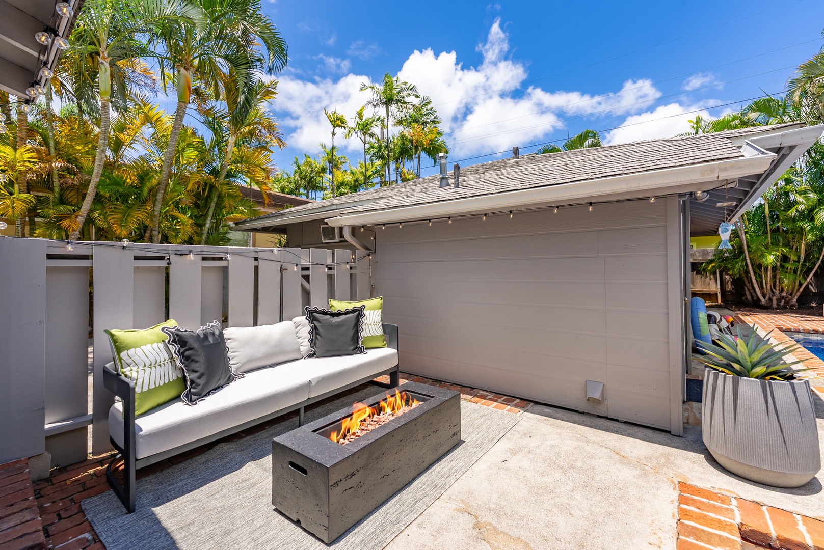 Honolulu Vacation Rentals, Ho'okipa Villa - Private outdoor patio where you can unwind under swaying palms, gathered around the warm glow of the firepit, surrounded by tropical greenery under the open sky.