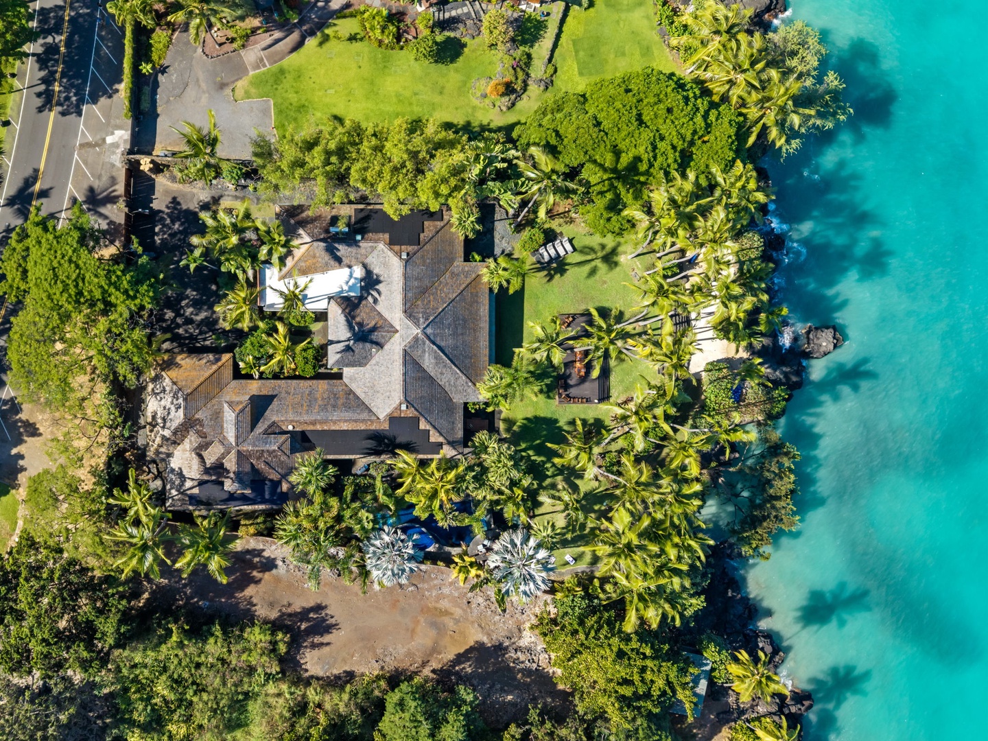 Kailua-Kona Vacation Rentals, Hahalua Bay Villa - Stunning aerial view of a tropical beachfront property surrounded by lush palm trees and pristine turquoise waters.