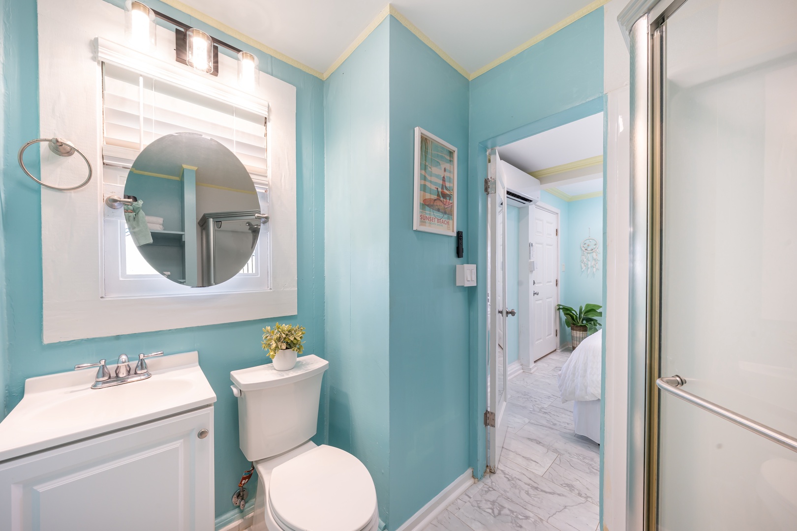 Hauula Vacation Rentals, Private Beach Paradise - Cool blue and a round mirror make the hallway bath feel calm.
