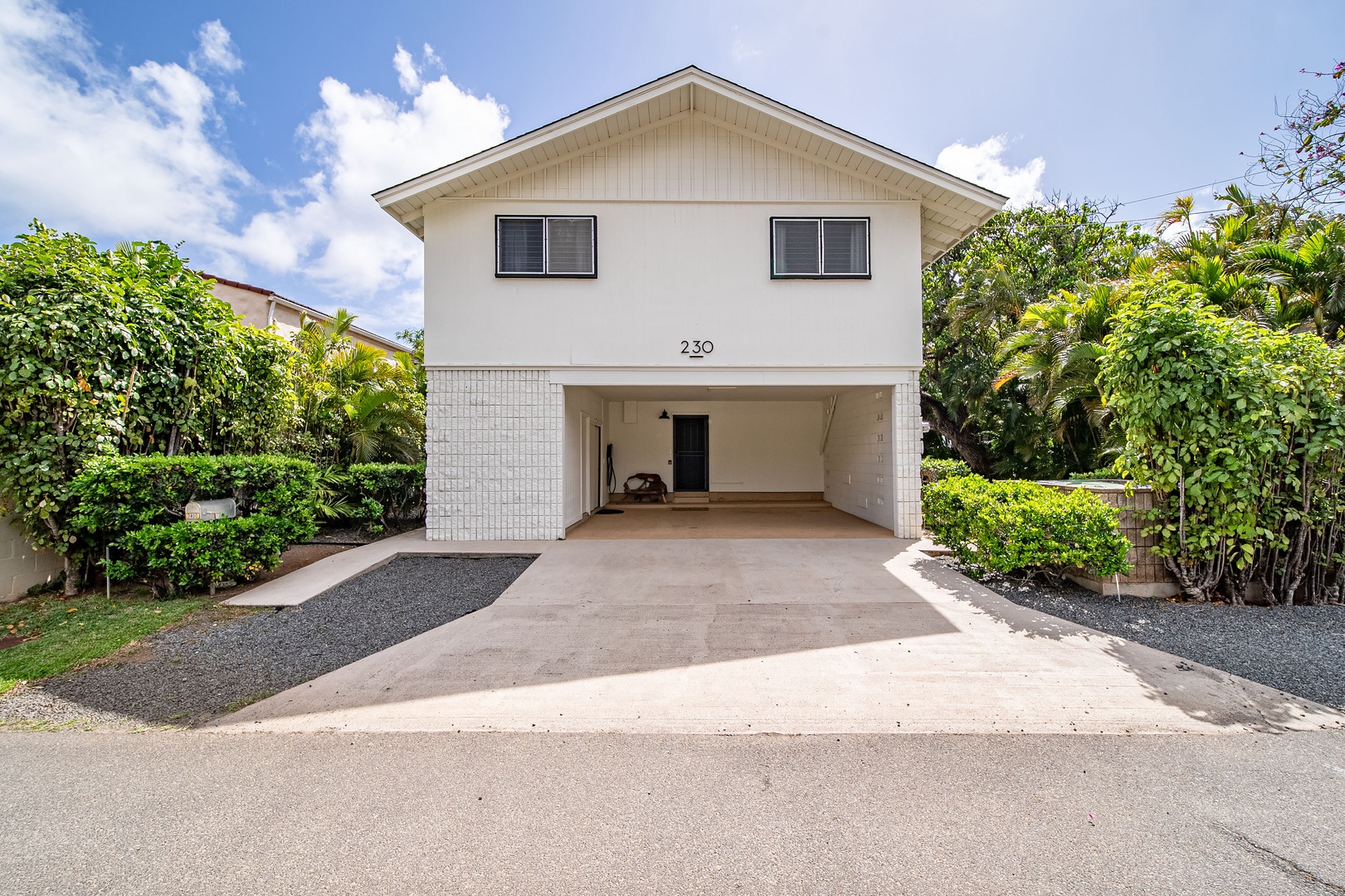 Honolulu Vacation Rentals, Honolulu Beachfront Retreat - Front view of the home featuring a spacious driveway and lush tropical greenery, welcoming you to your Hawaiian retreat.