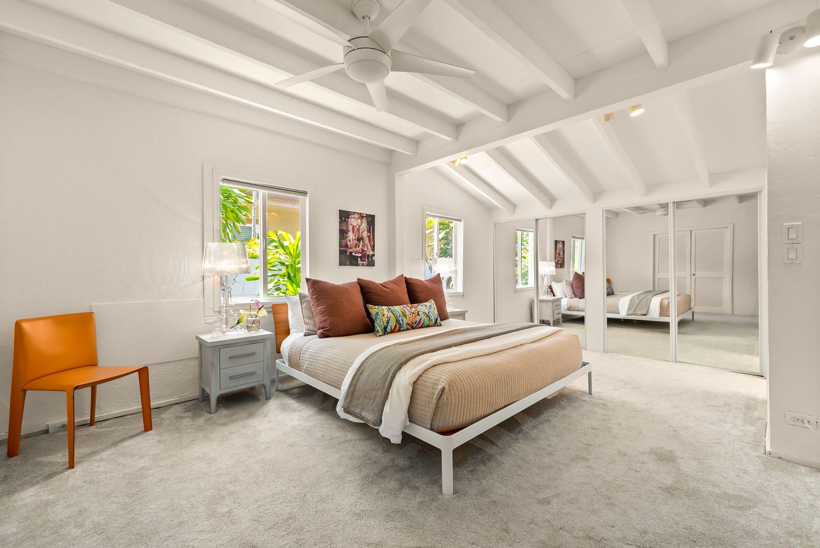 Honolulu Vacation Rentals, Ho'okipa Villa - Your airy bedroom features vaulted ceilings, a ceiling fan, and mirrored closet doors that amplify natural light from multiple windows overlooking lush greenery.
