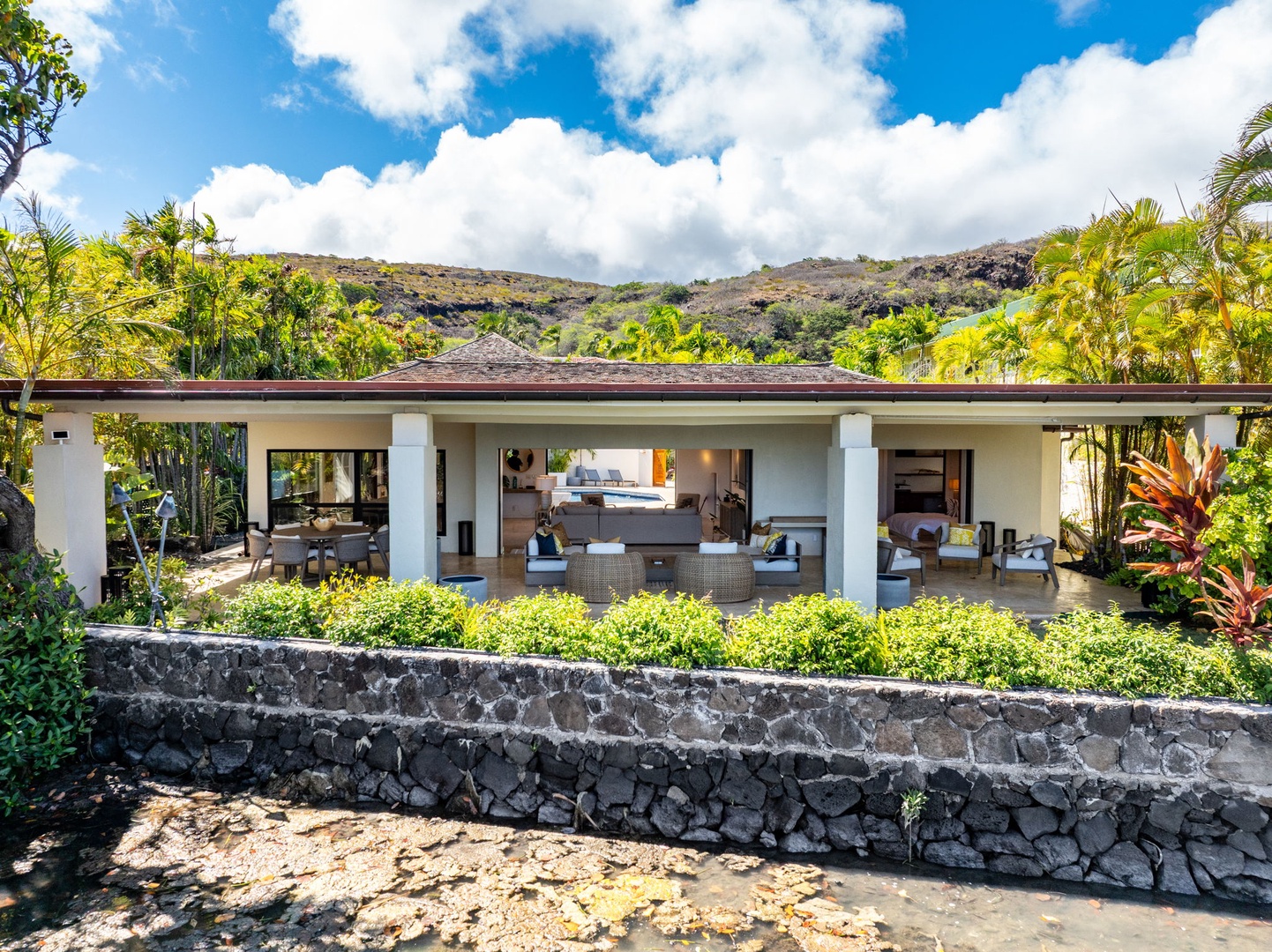 Honolulu Vacation Rentals, Honolulu Lagoonfront Villa - Covered lanai and lounge zones open toward the water and mountains beyond—classic indoor-outdoor island living.
