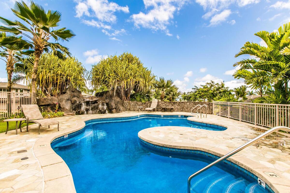 Princeville Vacation Rentals, Noelani Kai - Lava rock and tropical greenery frame the community pool, with a waterfall feature just beyond the deck.