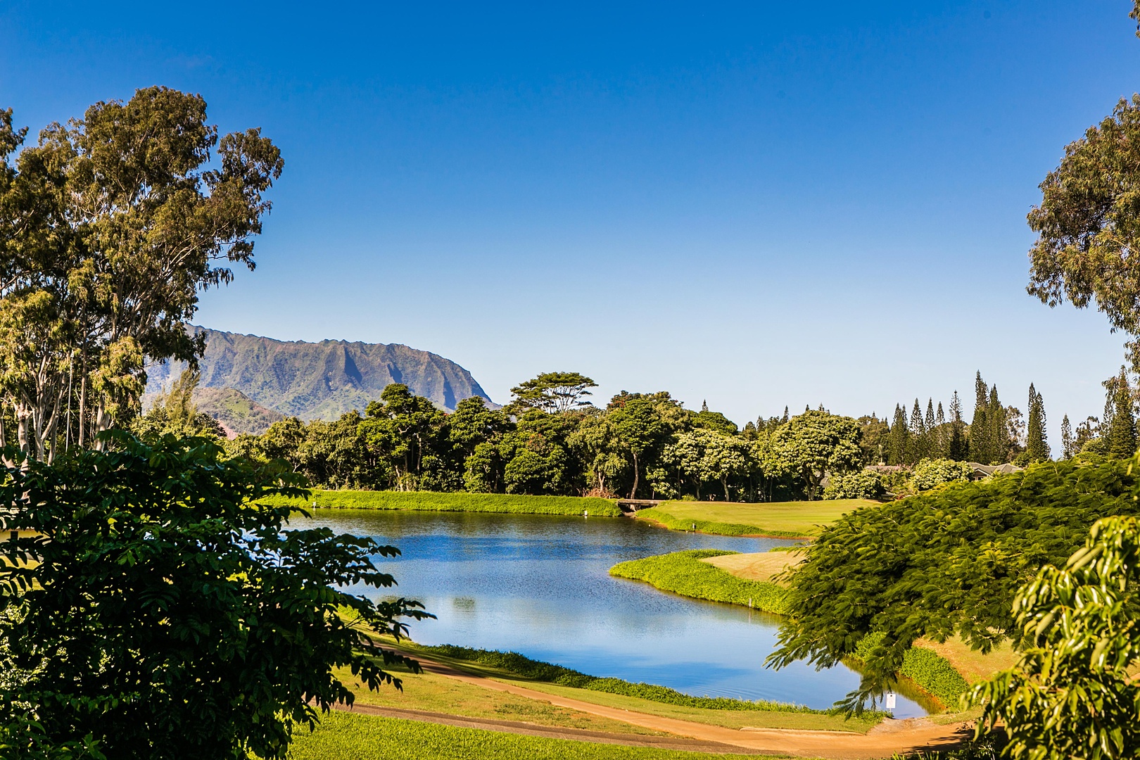 Princeville Vacation Rentals, Ola Hou - Entire Property - A serene golf course surrounded by lush trees and distant mountains.