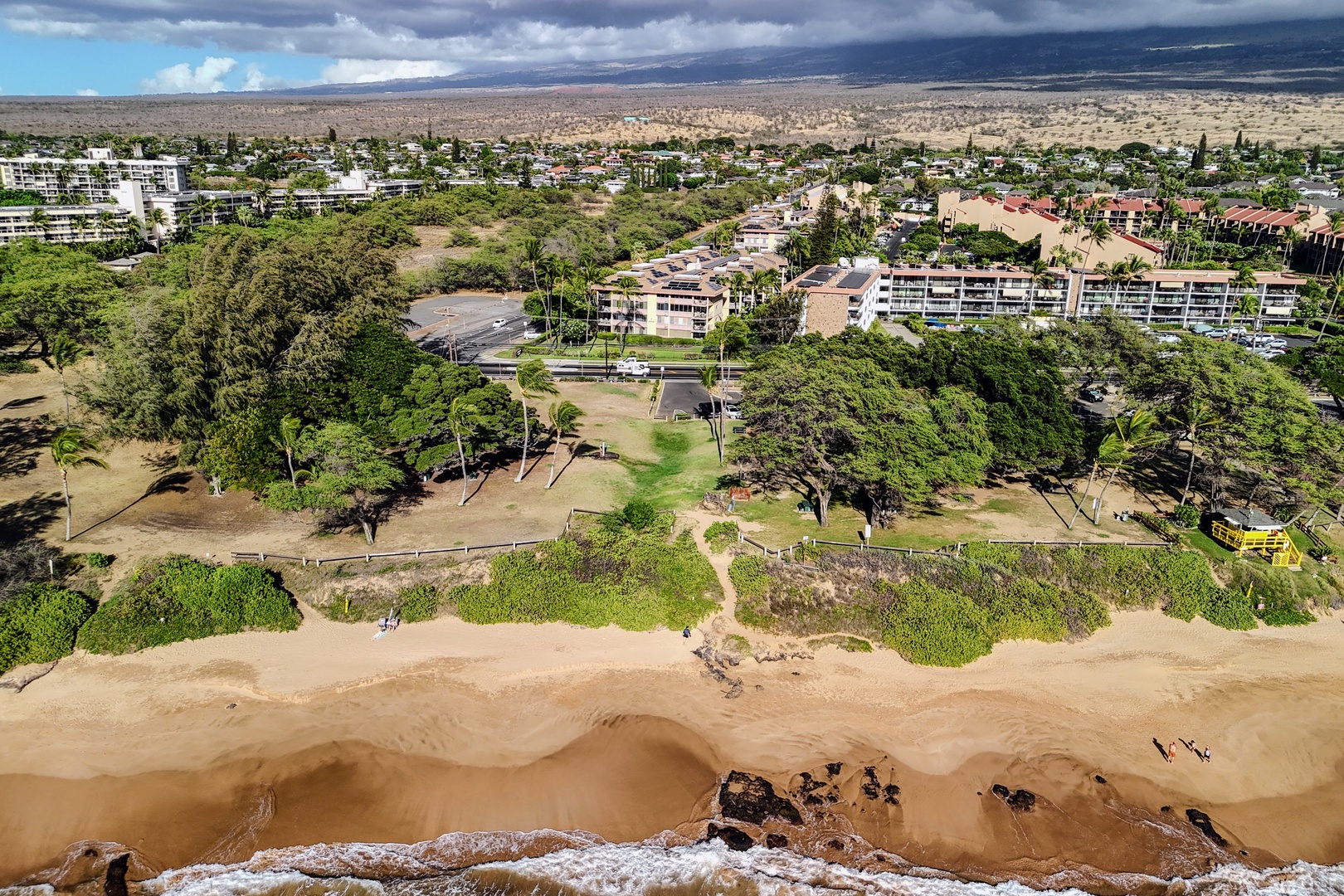 Kihei Vacation Rentals, Haleakala Shores A206 - A public beach park runs along the shoreline here, Haleakala Shores' rooftop solar panels visible just past the trees.