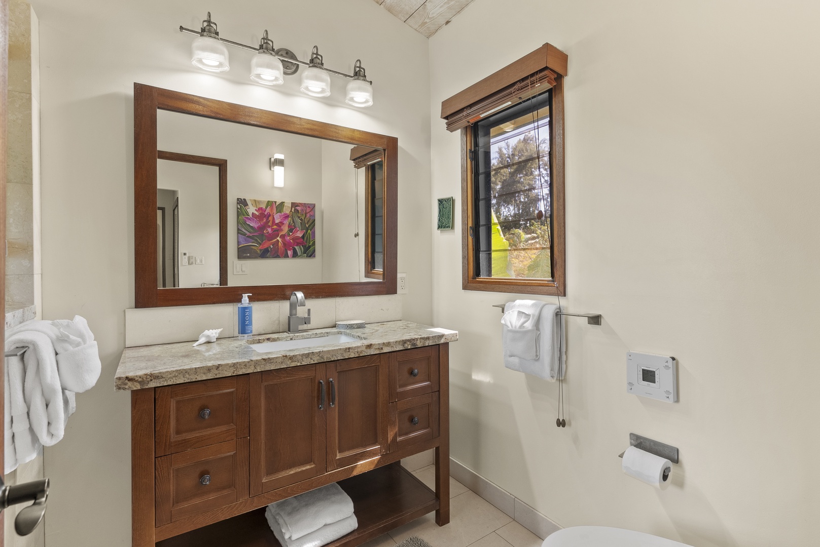 Haleiwa Vacation Rentals, Maluhia Beach House - A well-appointed bathroom with double sinks, rich wood cabinetry, and bright natural lighting.