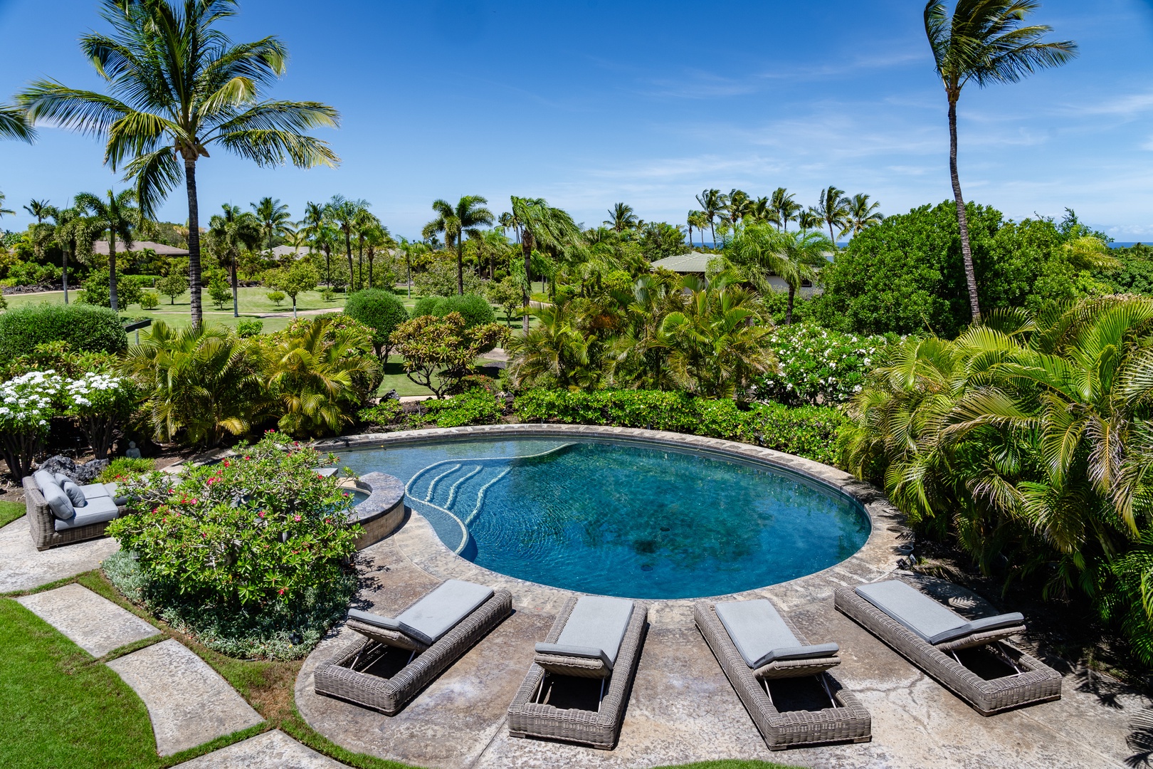 Kamuela Vacation Rentals, Mauna Lani Champion Ridge 22 - Beautiful circular pool surrounded by lush greenery and comfortable lounge chairs, offering a perfect spot to relax and enjoy the outdoors.