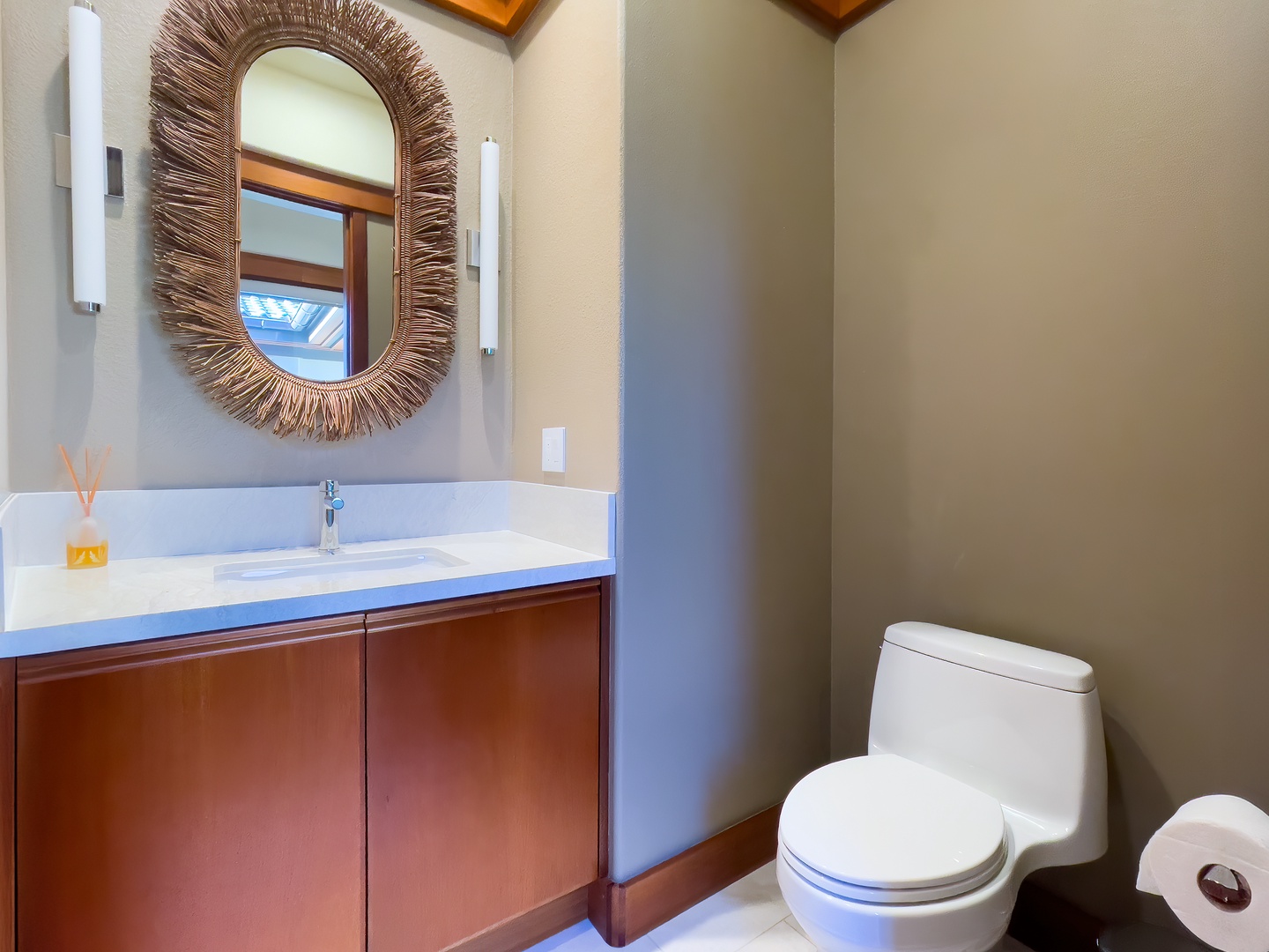 Kamuela Vacation Rentals, Champion Ridge Oasis - Elegant powder room located near the kitchen featuring a modern vanity, a statement mirror, and warm wood accents for a refined touch.