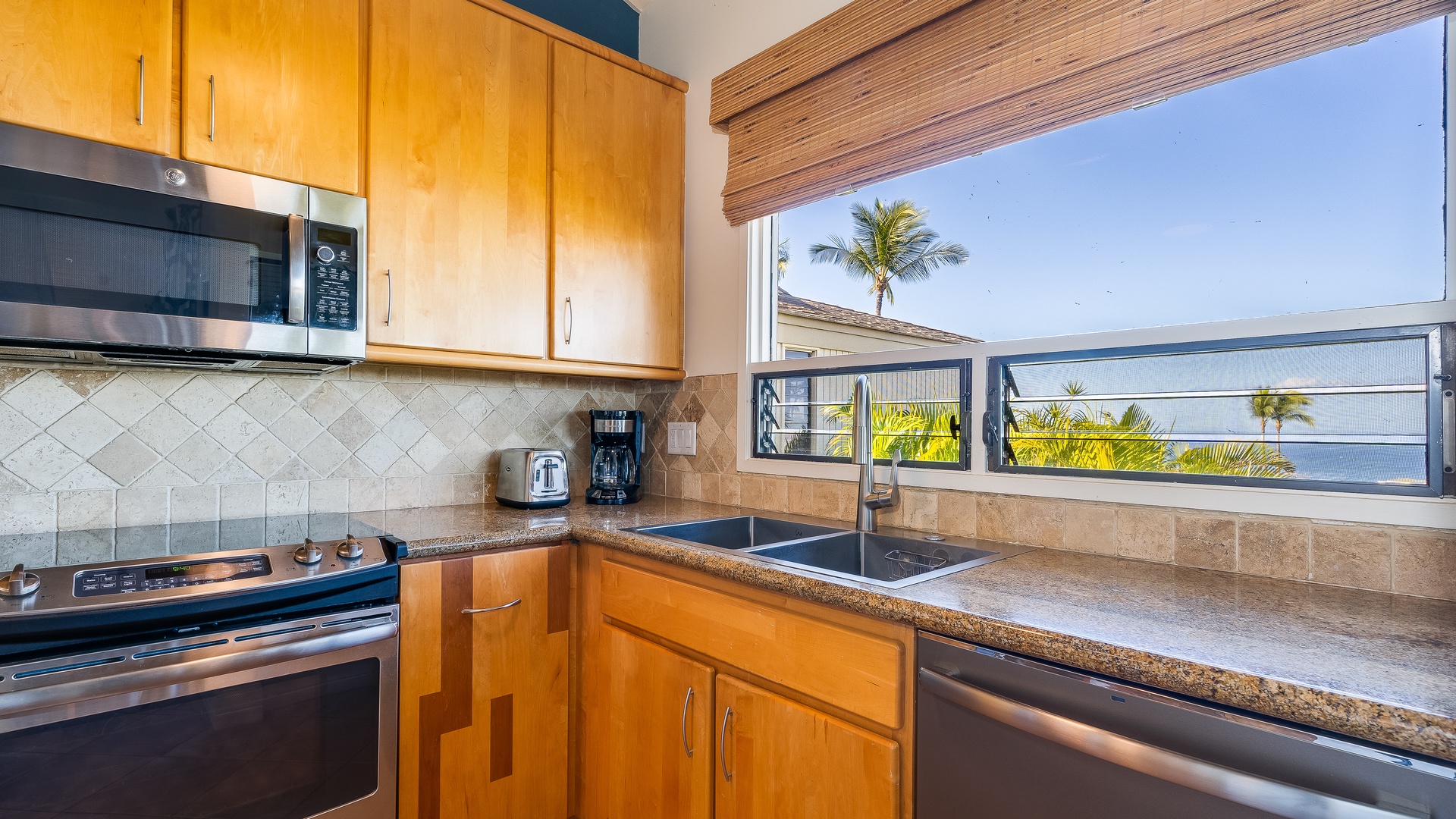 Kihei Vacation Rentals, Wailea Ekolu 1106 - A bright kitchen with modern appliances, ample counter space, and a scenic view of the tropical landscape from the window