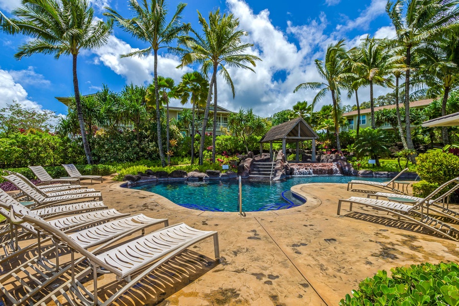 Princeville Vacation Rentals, Kaimana Villa - Resort-style pool surrounded by tropical palms and lounge chairs in a beautifully landscaped setting.