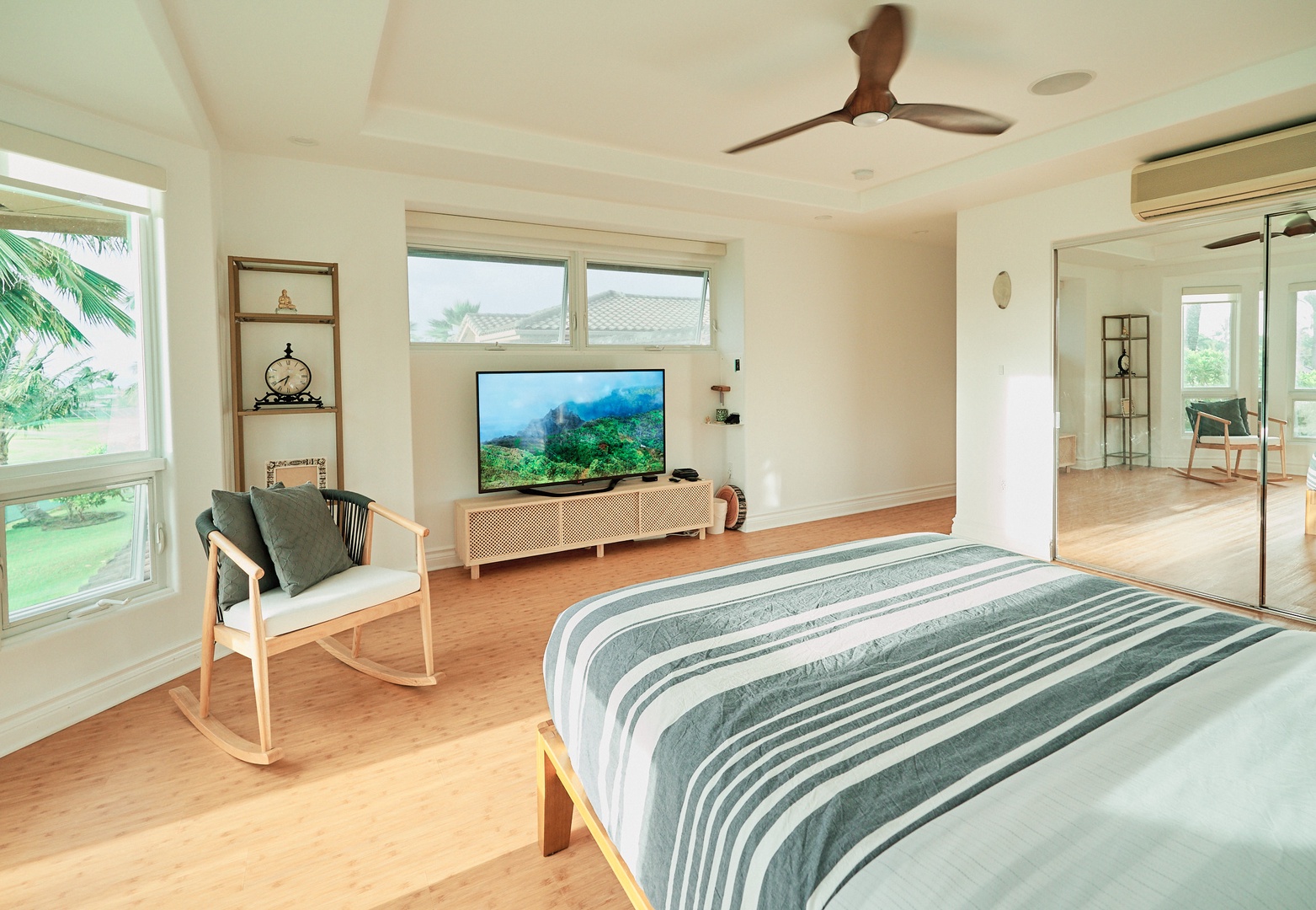 Princeville Vacation Rentals, Hale Kai - Unwind in your spacious bedroom with modern amenities, cozy seating, and serene garden views through large windows.