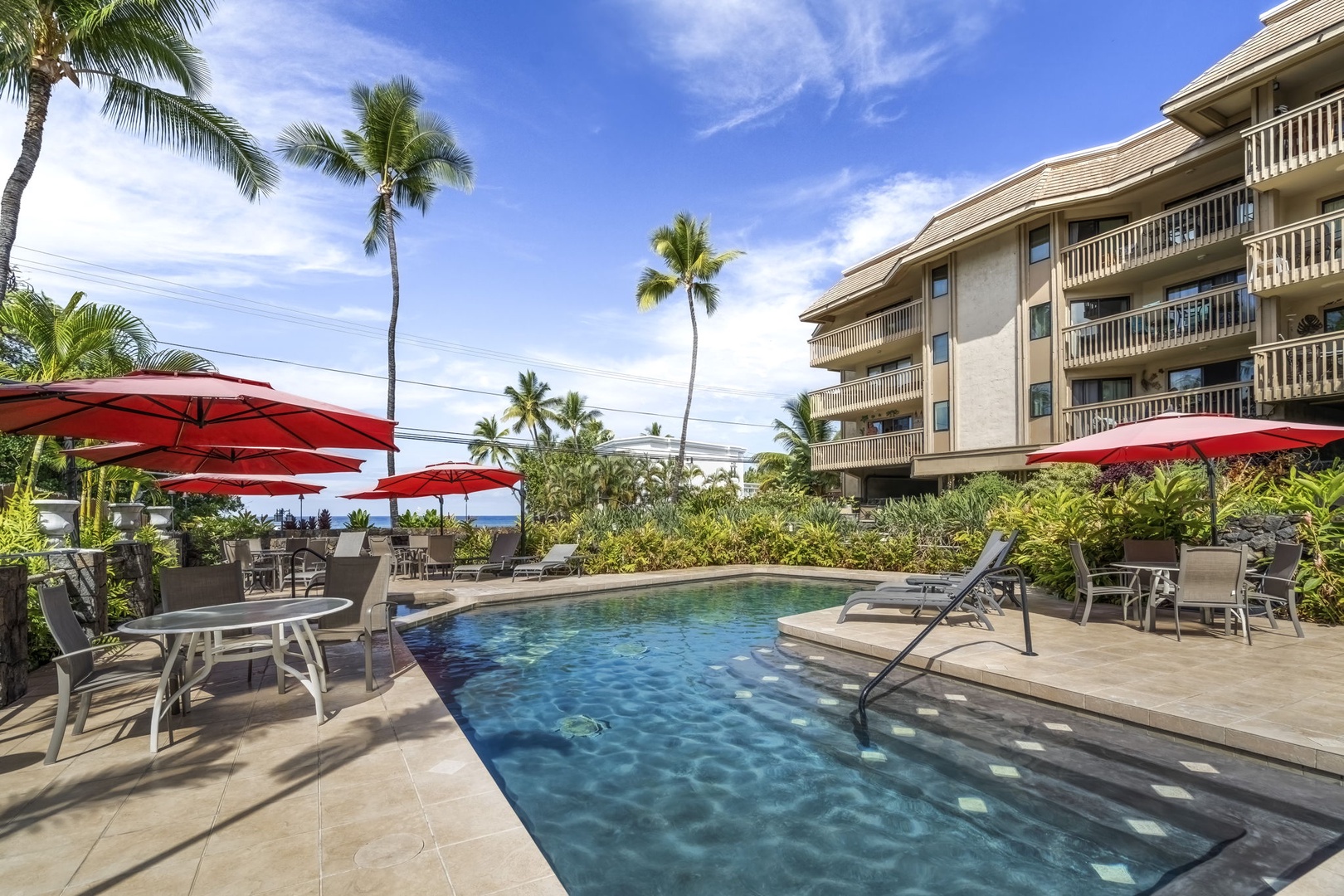 Kailua Kona Vacation Rentals, Royal Kahili 401A - Poolside retreat with seating for eight under vibrant red umbrellas, ideal for unwinding.