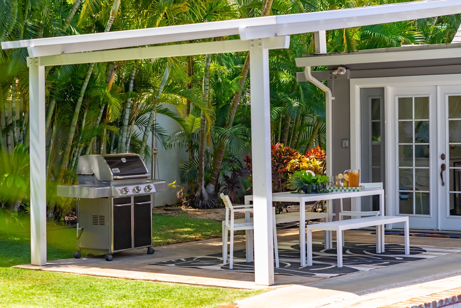 Honolulu Vacation Rentals, Ho'okipa Villa - Your private patio awaits with tropical garden views, perfect for outdoor dining and grilling under the covered pergola. Relax at the table, enjoy colorful landscaping, and step out to lush greenery.