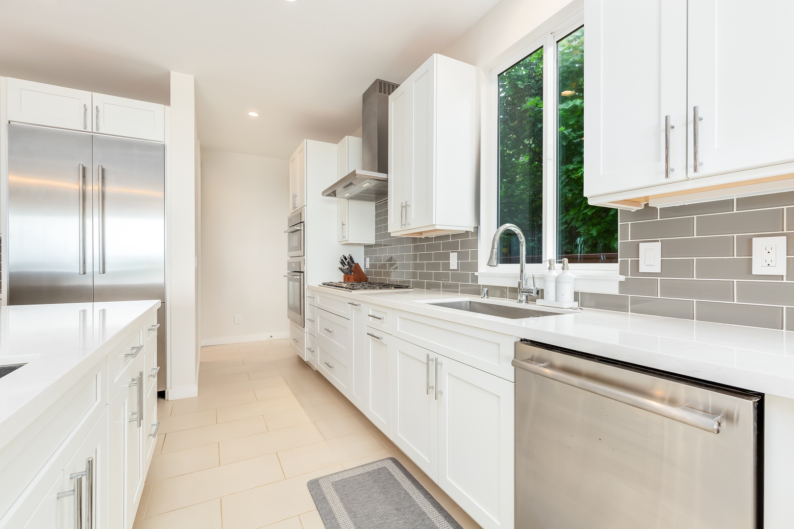 Laie Vacation Rentals, Majestic Mahakea Oceanfront Oasis - Modern kitchen with subway tile backsplash, a farmhouse sink, and stainless steel finishes.