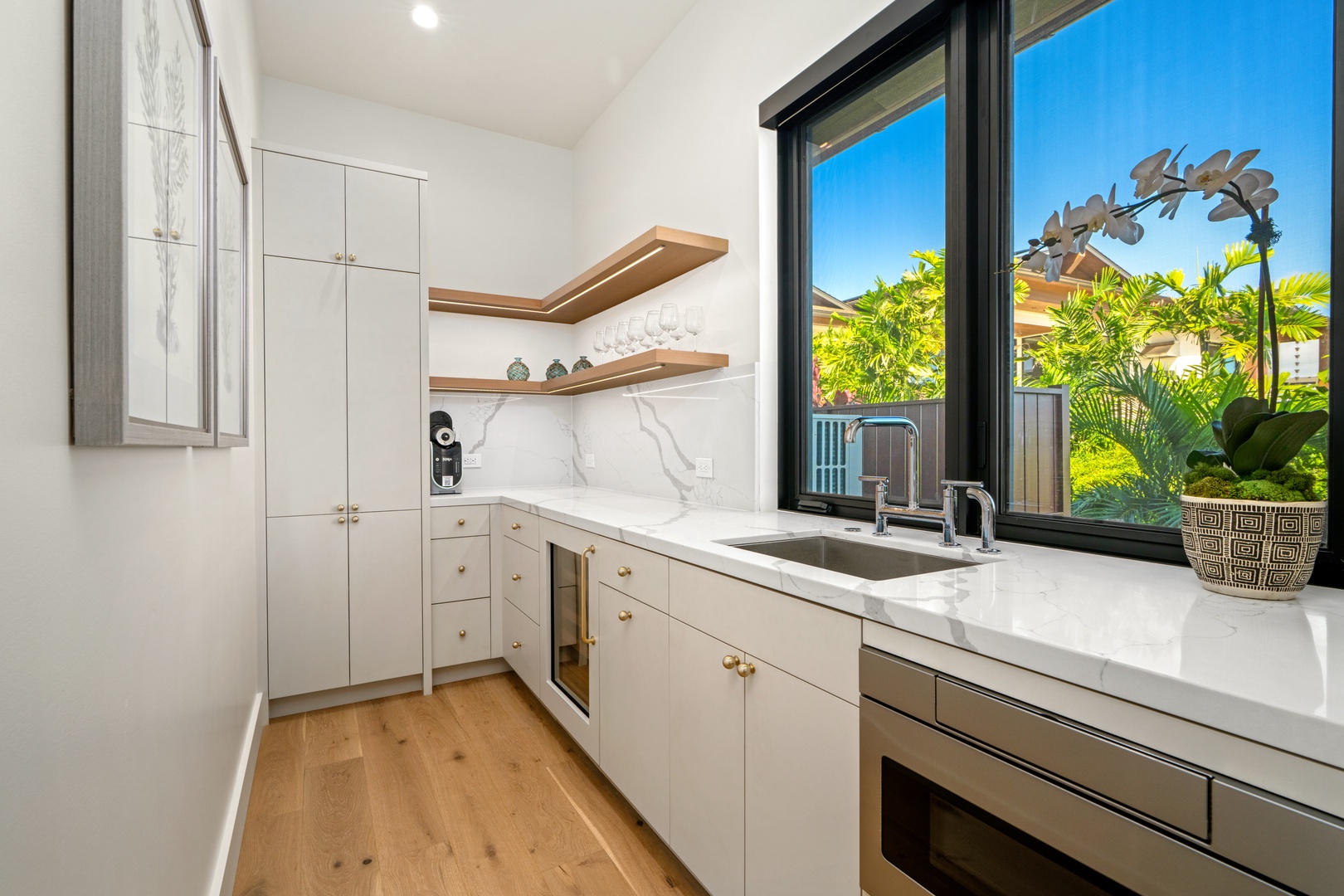 Koloa Vacation Rentals, Hale Laule'a at Kukui'ula - This modern kitchen features marble countertops and garden views, perfect for preparing meals while enjoying tropical greenery outside.
