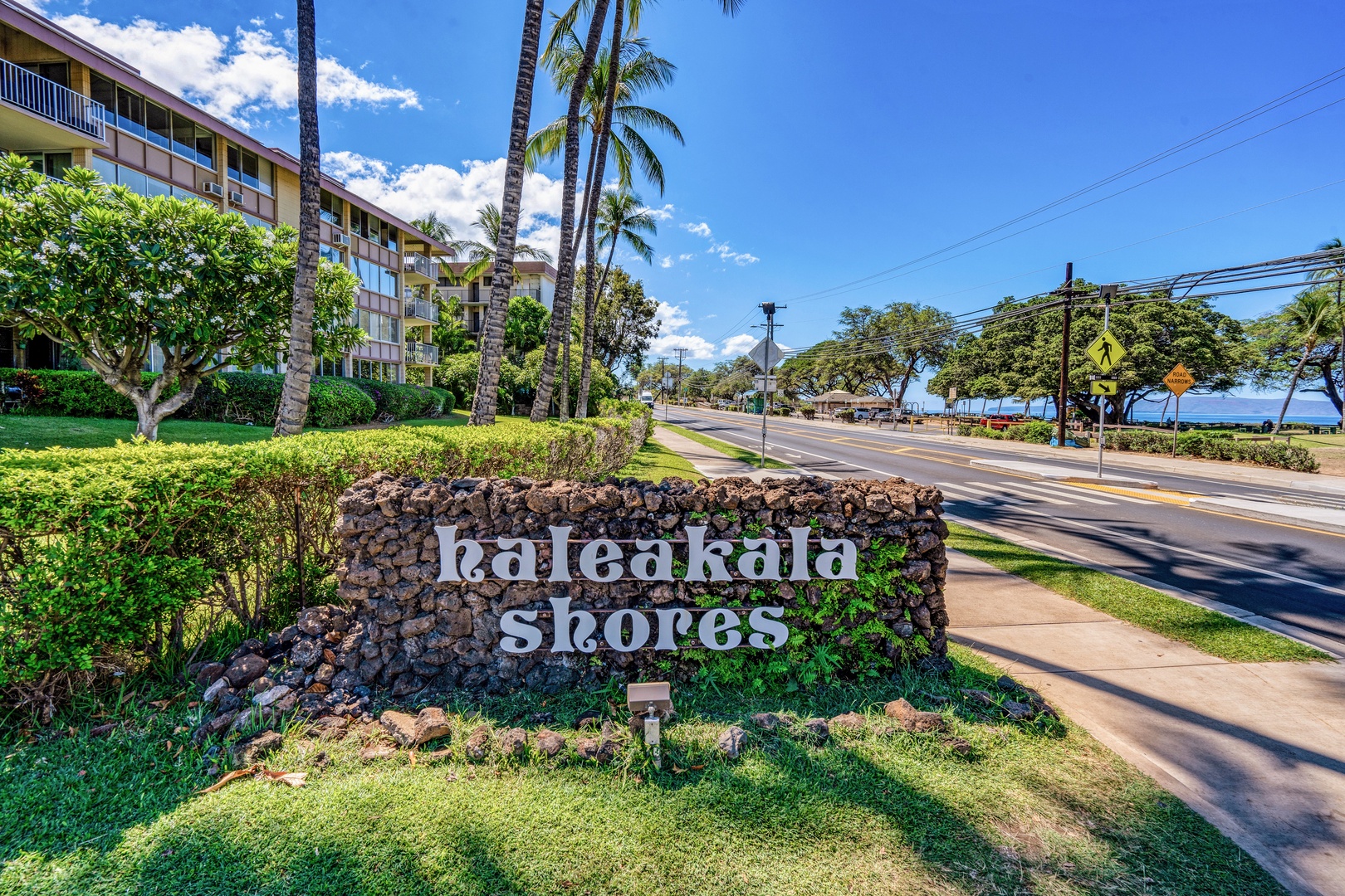 Kihei Vacation Rentals, Haleakala Shores A206 - The lava-rock Haleakala Shores sign marks the turn in, with a sliver of ocean already visible down the road.