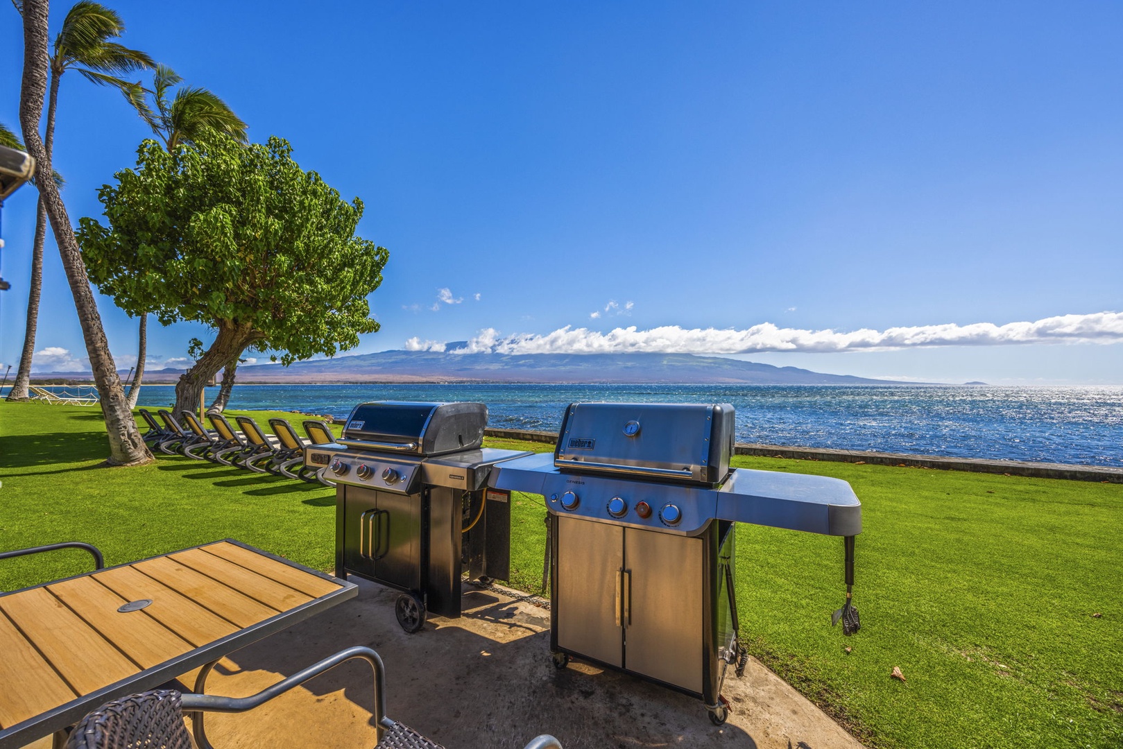 Wailuku Vacation Rentals, Milowai 310 - Two Weber grills line up oceanfront, with a row of lounge chairs and the mountains rising across the channel.