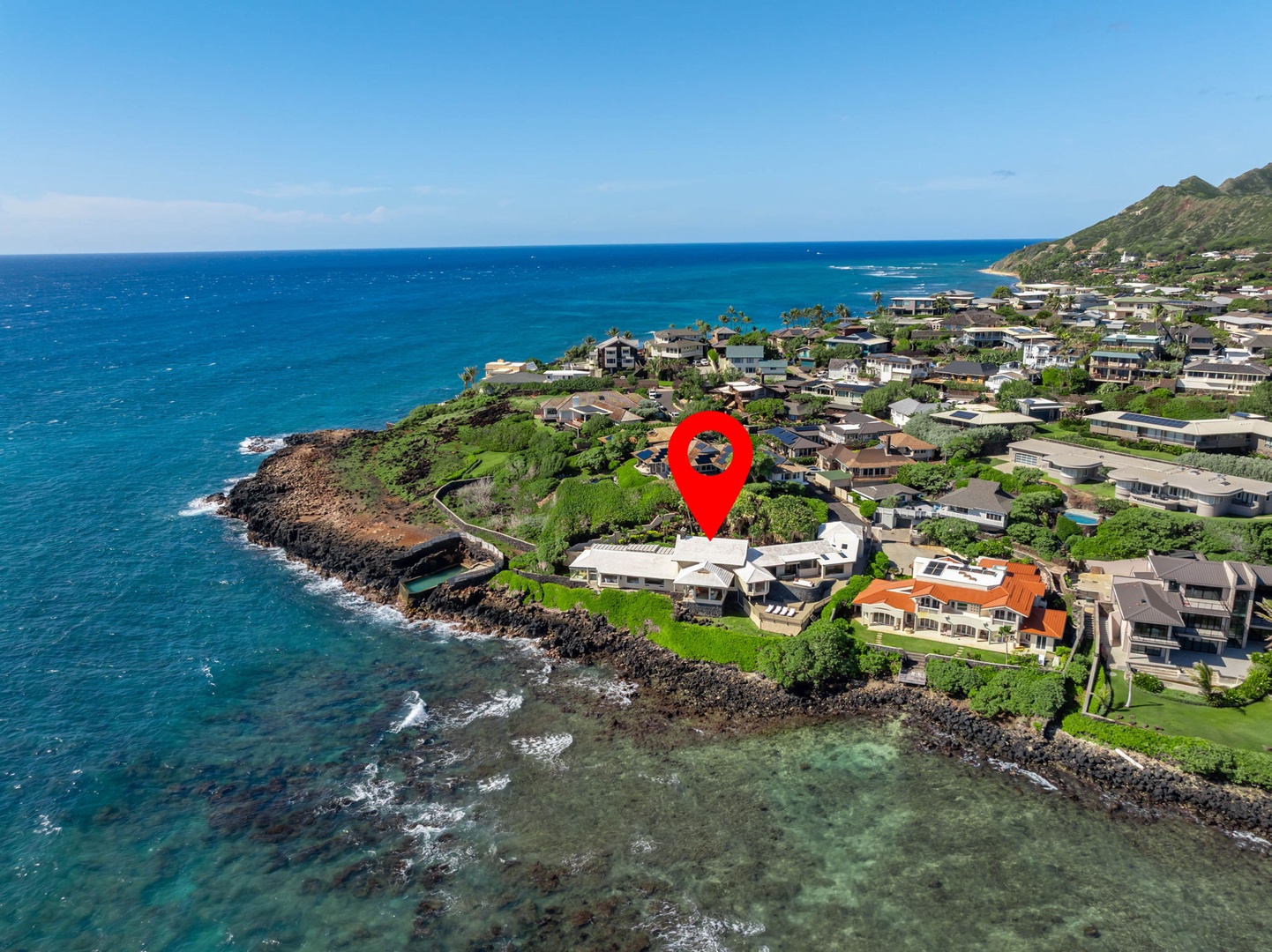 Honolulu Vacation Rentals, Black Point Ocean Villa - Aerial view showcasing the property's prime oceanfront location within a scenic coastal community nestled between mountains and turquoise waters.