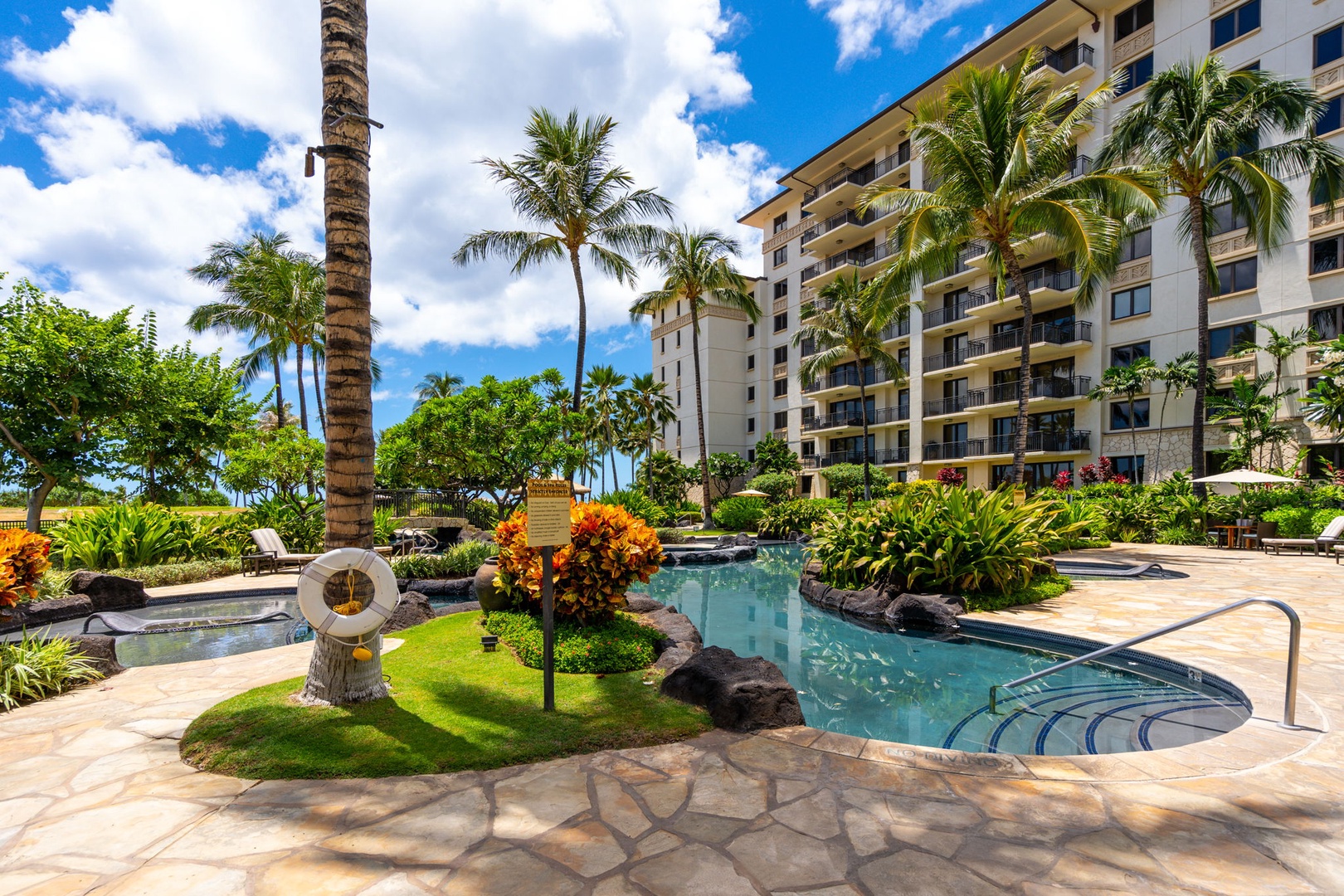 Kapolei Vacation Rentals, Ko Olina Beach Villas B604 - Resort pool area surrounded by lush tropical landscaping and palm trees under blue Hawaiian skies.