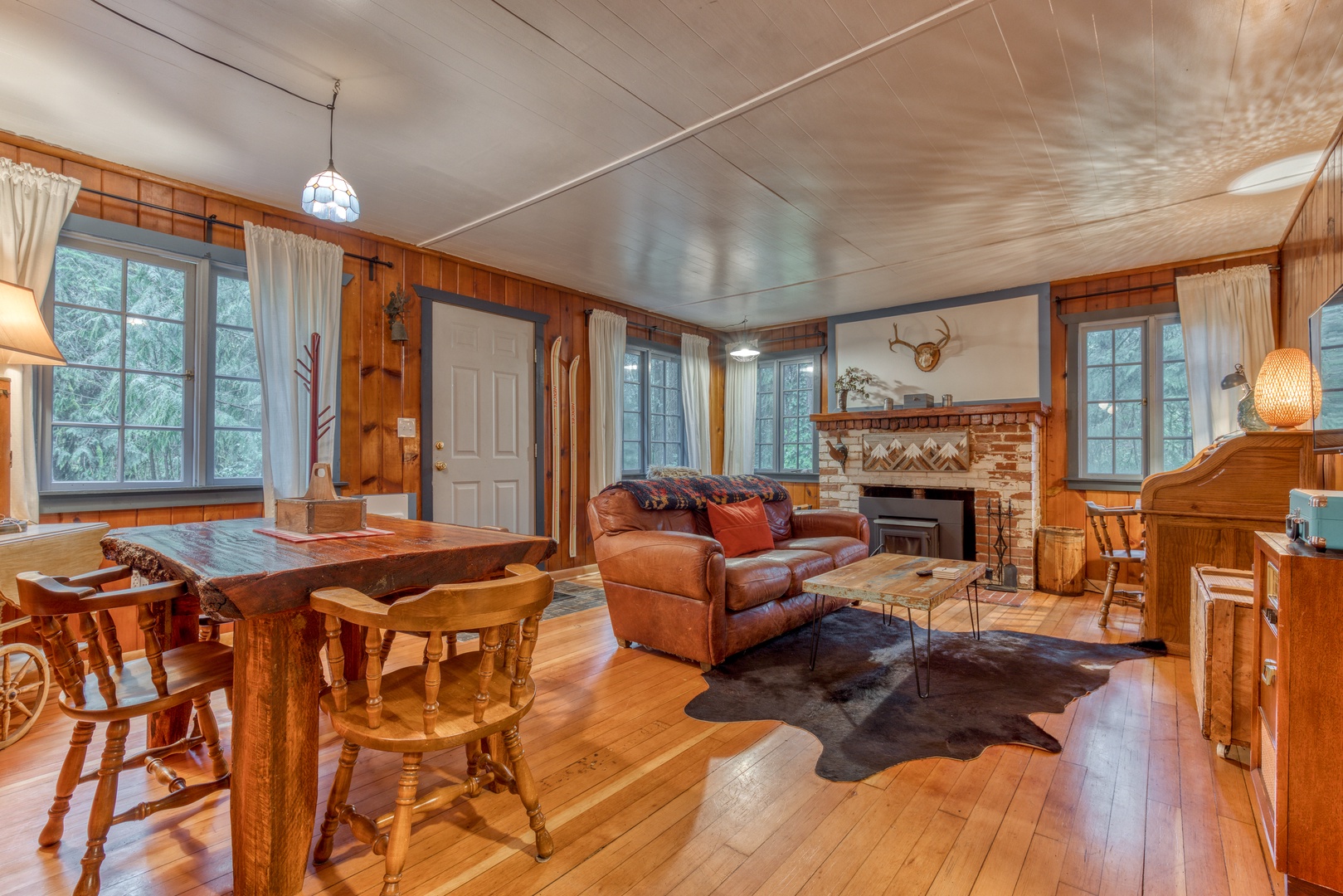 Brightwood Vacation Rentals, Springbrook Cabin - The vibrant living area is adorned with a comfy leather sofa, a vintage chair, a large flatscreen Smart TV, a large antique desk, and a cozy new fireplace with starter firewood.